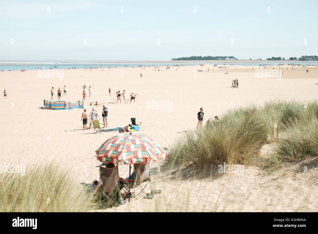 Persone su una spiaggia di sabbia bianca a Wells accanto al mare in Norfolk, Regno Unito, su un caldo weekend festivo Foto Stock