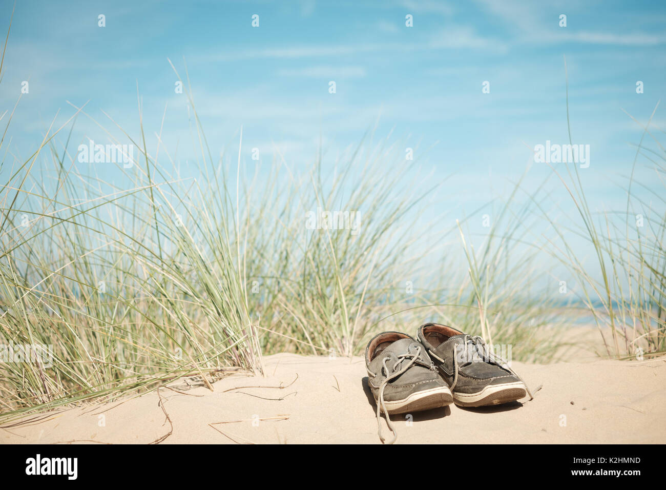 Uomo di scarpe abbandonate su una duna di sabbia su una soleggiata spiaggia estate in Norfolk, Regno Unito Foto Stock