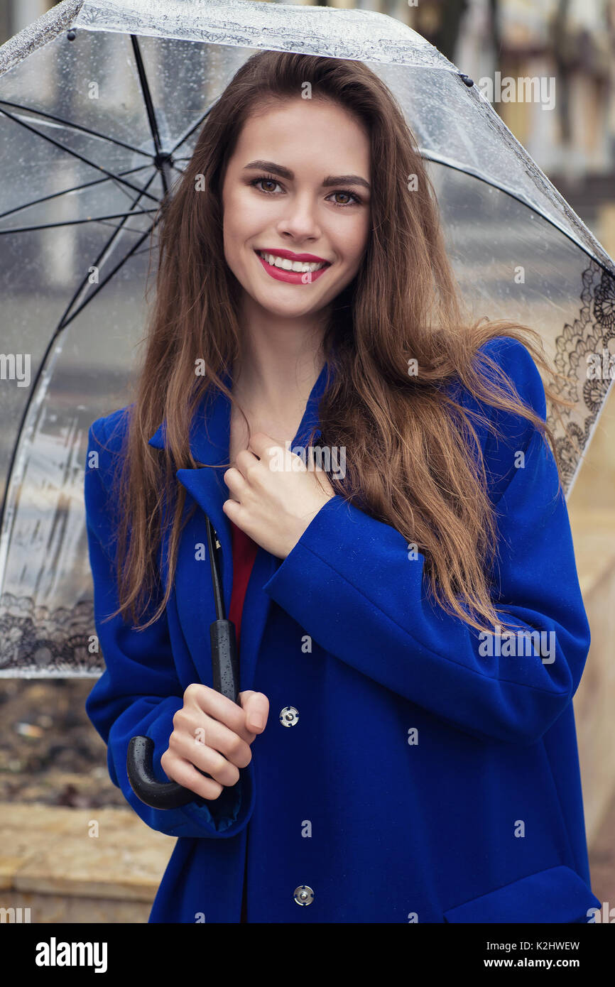 Ritratto di giovane bella ragazza che si nasconde sotto un ombrello da una piccola pioggia. Visualizzazione del modello è diretto alla fotocamera Foto Stock