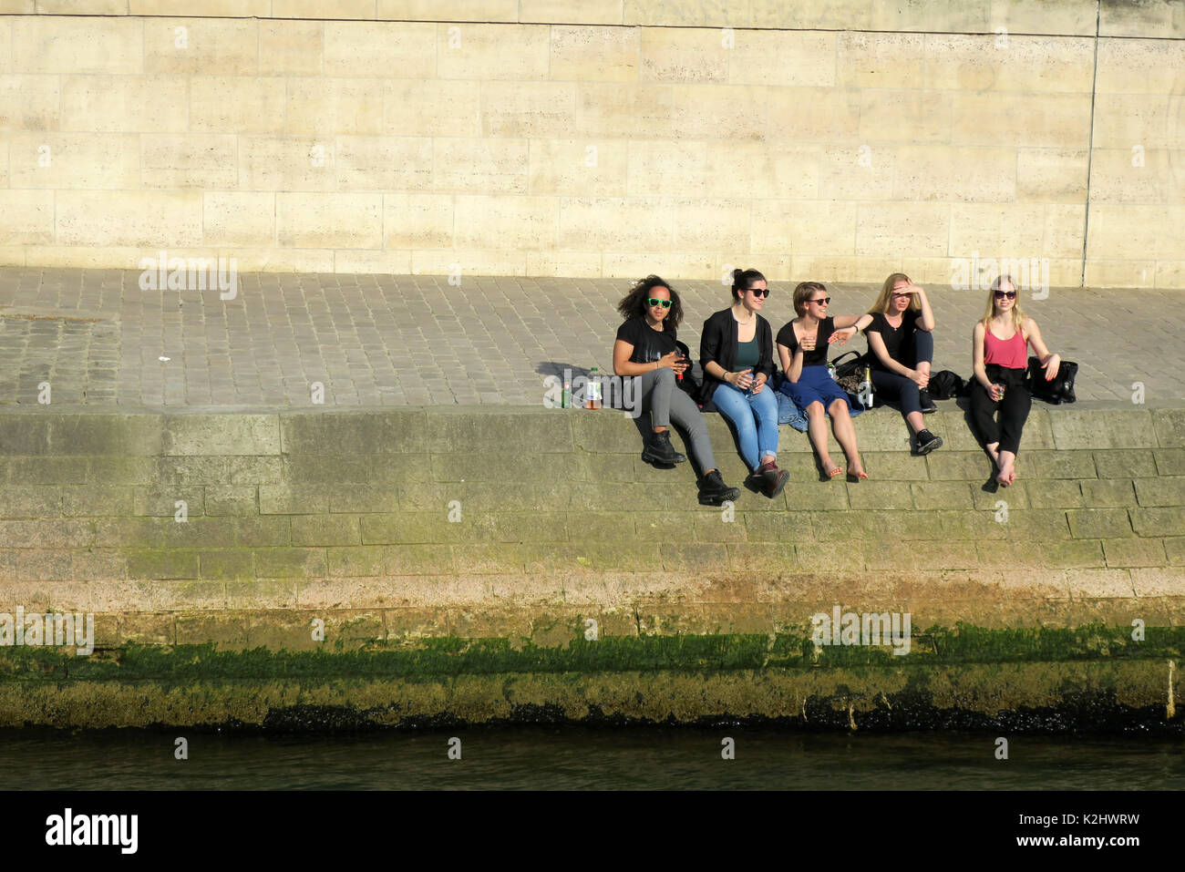 Le persone a rilassarsi sulla parete lungo il Fiume Senna a Parigi, Francia. Foto Stock