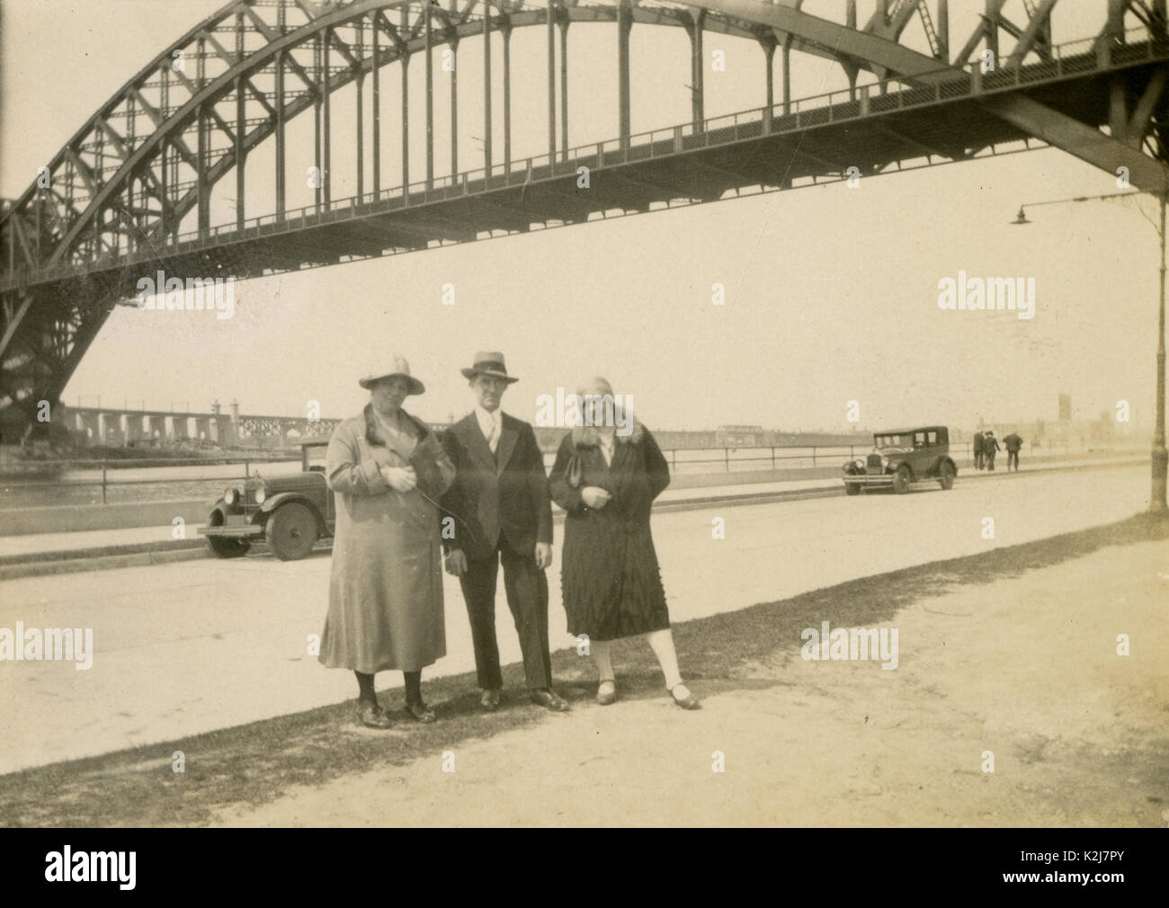 Antique c1920 fotografia, familiari pongono di fronte l'Hell Gate Bridge. L'Hell Gate Bridge è un 1,017-piede (310 m) in acciaio arco attraverso il ponte ferroviario in New York City. Il ponte attraversa il Hell Gate, lo stretto dell'East River, tra Astoria nel Queens e Randalls reparti e isole in Manhattan. Fonte: fotografia originale. Foto Stock