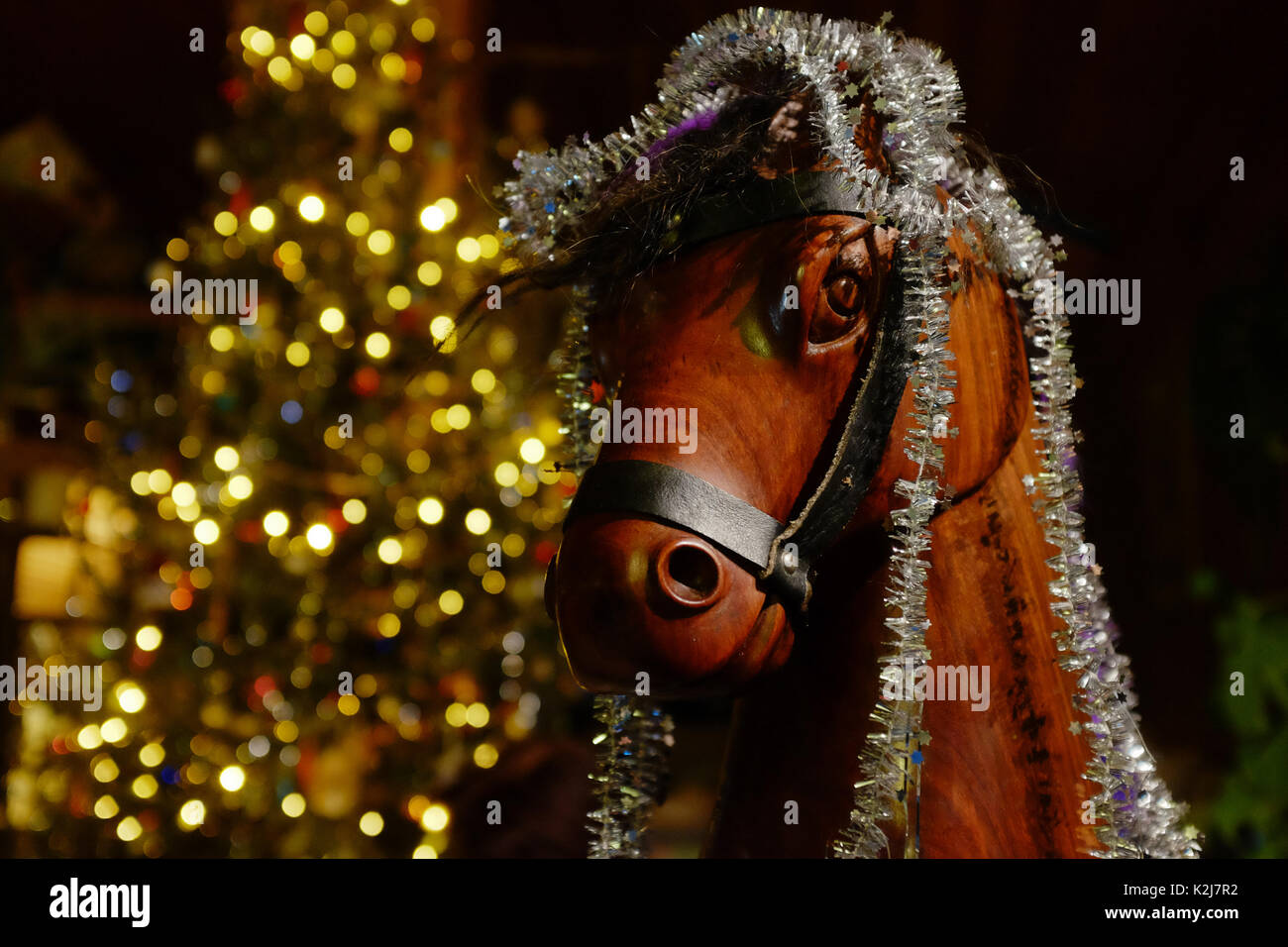 Hobby in legno cavallo adornata con tinsel argento nella parte anteriore del bokeh luce albero di Natale Foto Stock