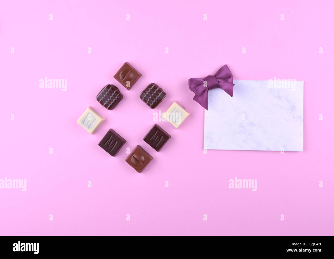 Raccolta di deliziose praline di cioccolato sulla tendenza rosa sfondo. Piatto stile di laici. Posto per il vostro testo. Foto Stock