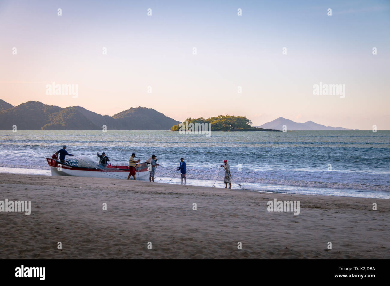 I pescatori in spiaggia con la Ilha das Cabras isola in background - Balneario Camboriu, Santa Catarina, Brasile Foto Stock