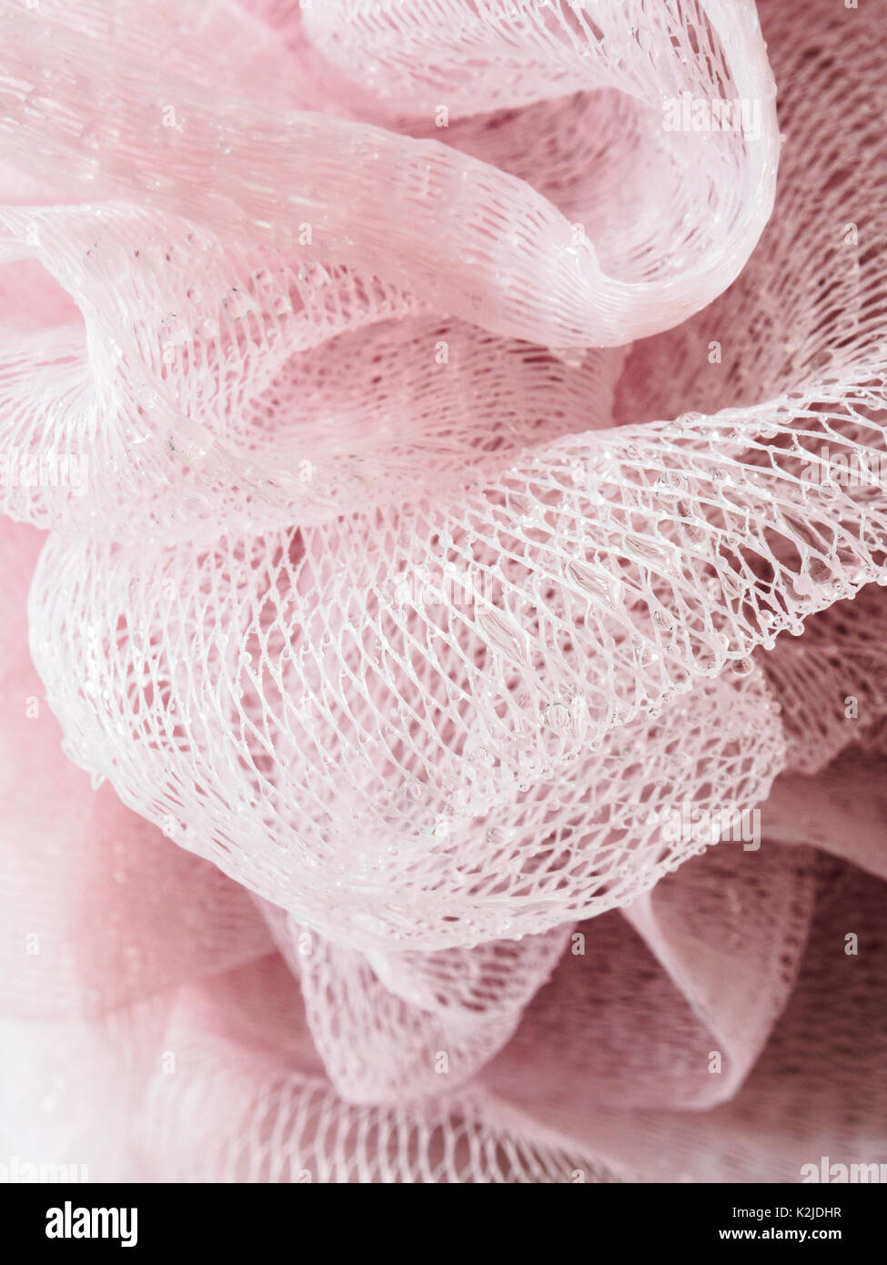 Plastica rosa loofa igiene scrubber coperti di gocce di acqua Foto Stock