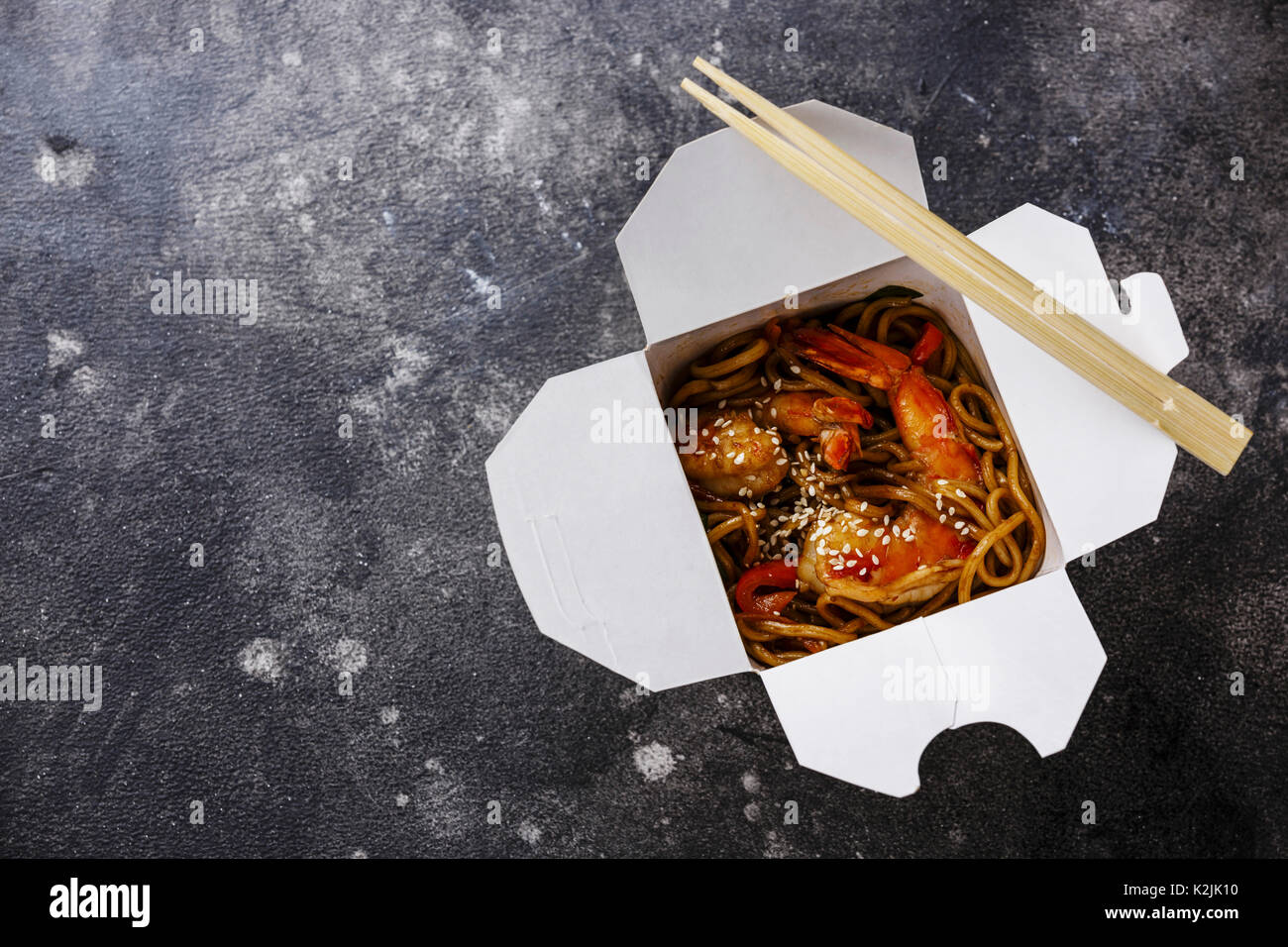 Udon Noodles saltati in padella con gamberi tigre asiatica nella casella estrarre cibo su sfondo scuro spazio copia Foto Stock