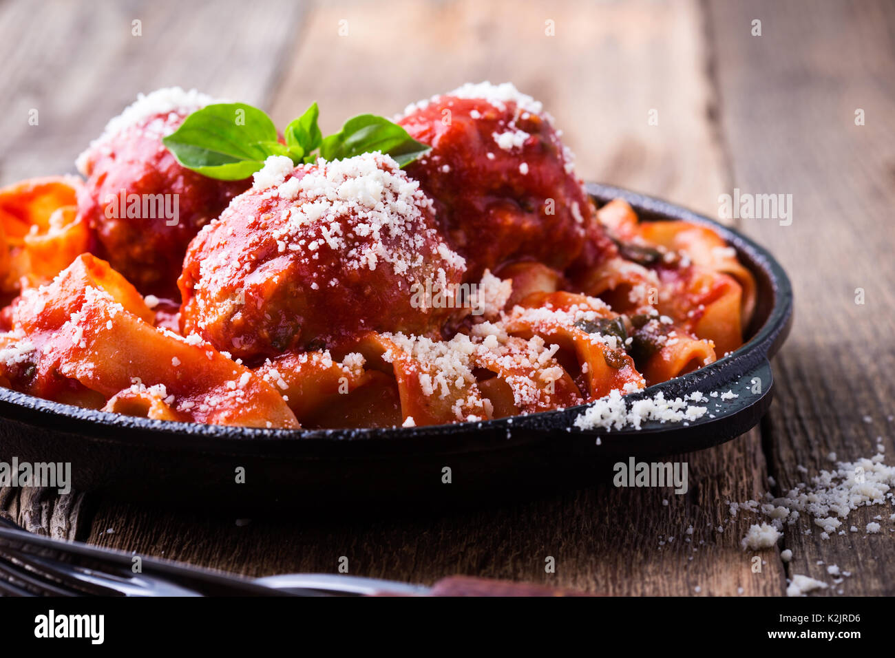 In casa tradizionale pasta italiana pappardelle con polpette di carne e erbe basilico servito con Grana Padano formaggio sulla tavola in legno rustico Foto Stock