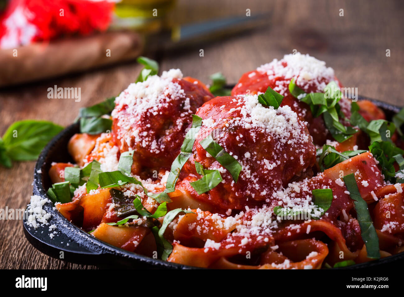 In casa tradizionale pasta italiana pappardelle con polpette di carne e erbe basilico servito con Grana Padano formaggio sulla tavola in legno rustico Foto Stock
