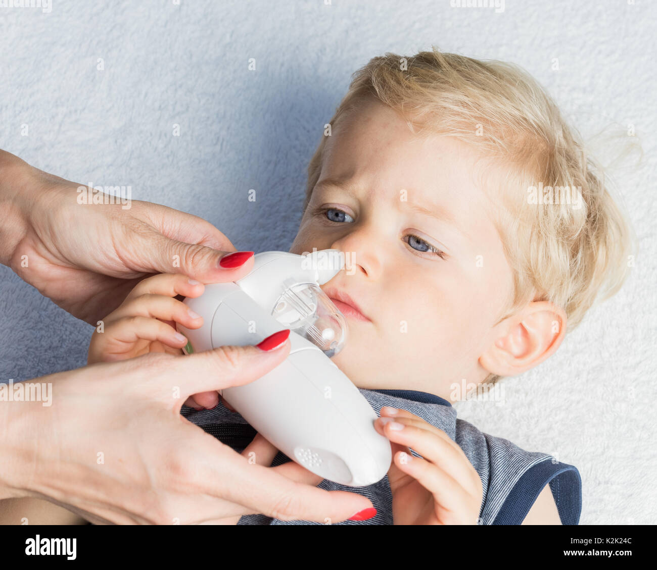 Madre con bambino elettrico Aspiratore nasale. Lei sta facendo una aspirazione di muco per venti mesi baby boy. Foto Stock