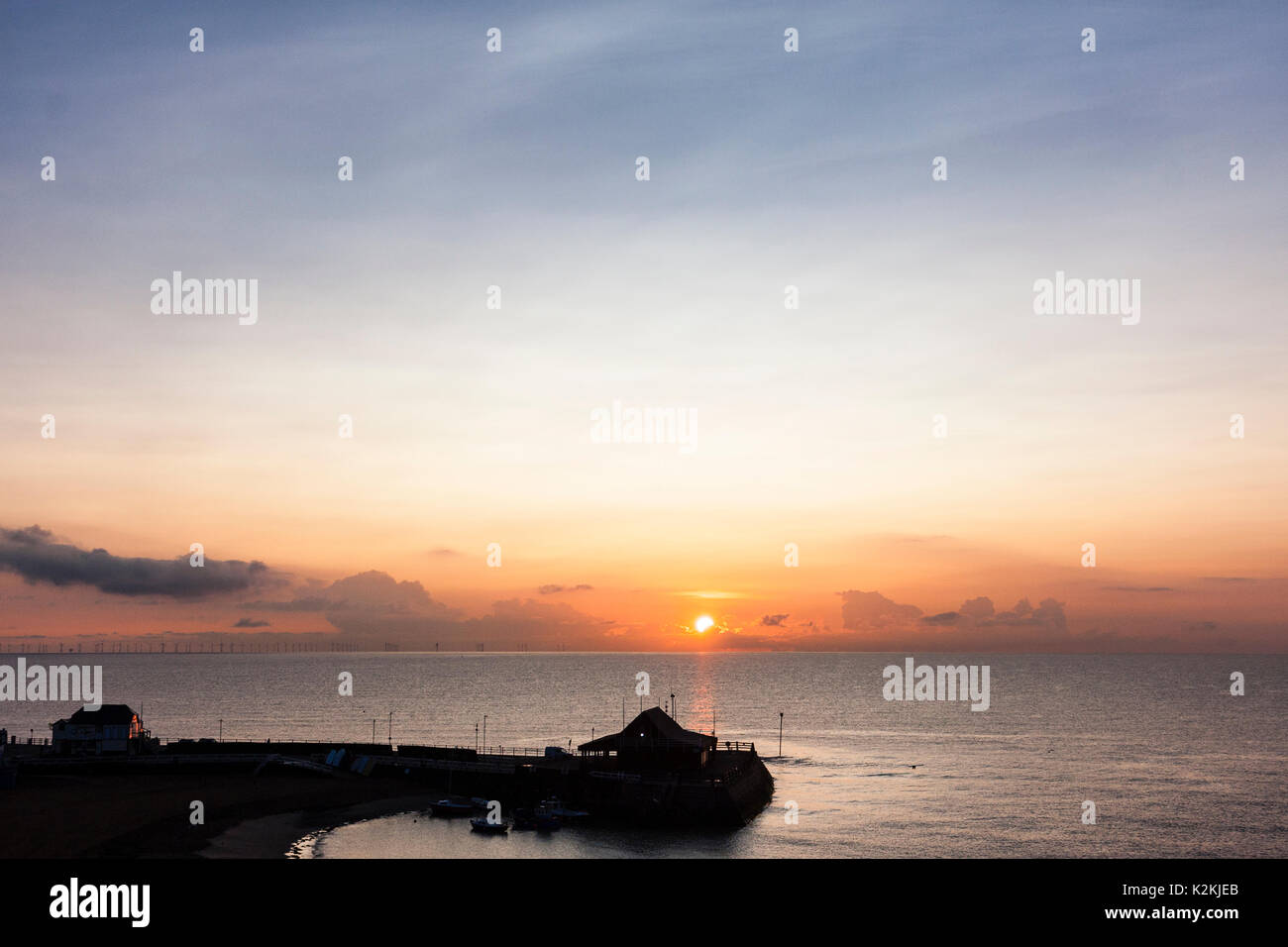 Il sorgere del sole sopra lo strato di cloud appena sopra il livello del mare, il canale in inglese, con la silhouette di Broadstairs Harbour in primo piano. Foto Stock