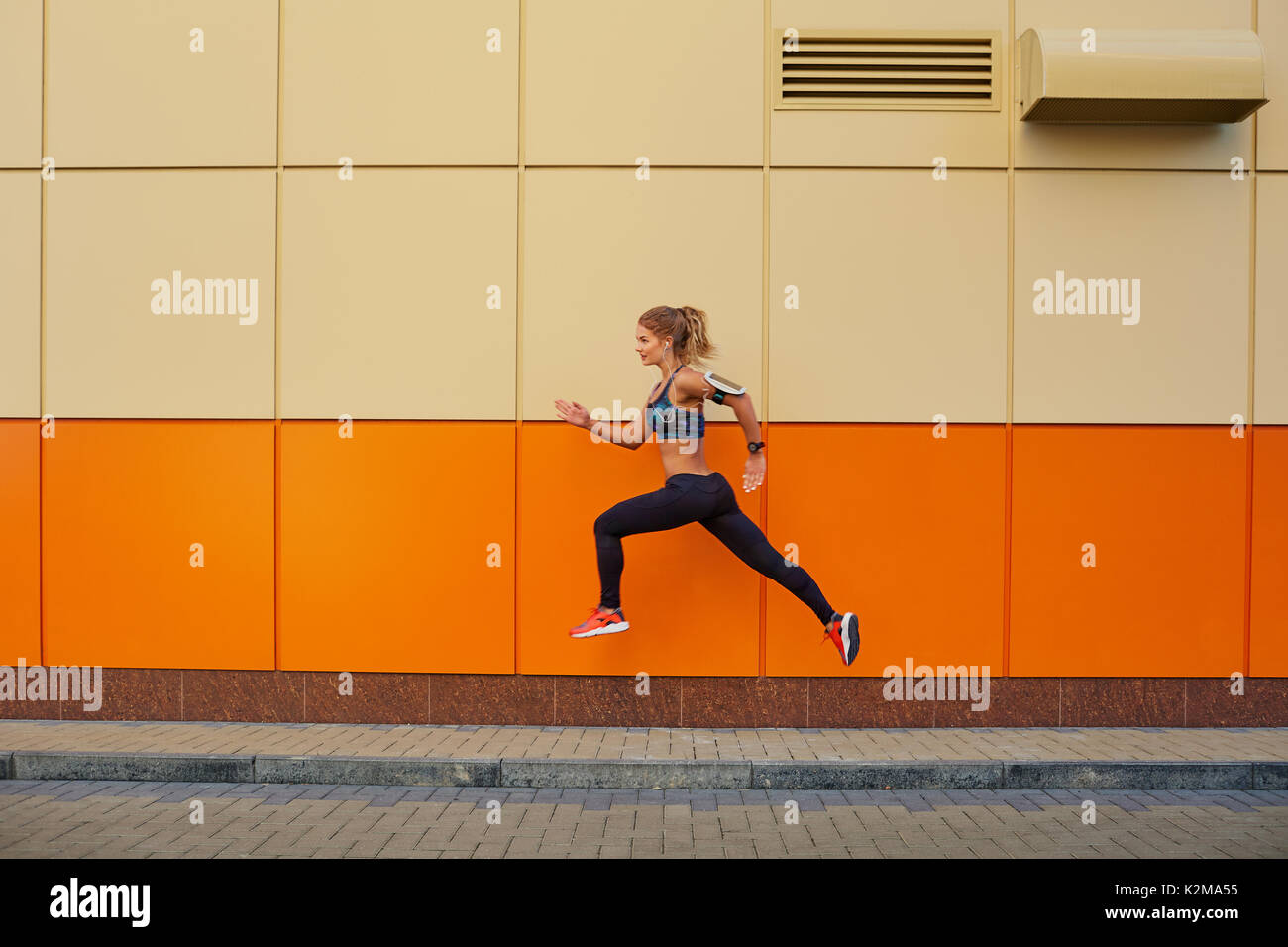 La ragazza sportiva ha saltato su uno sfondo arancione. Foto Stock