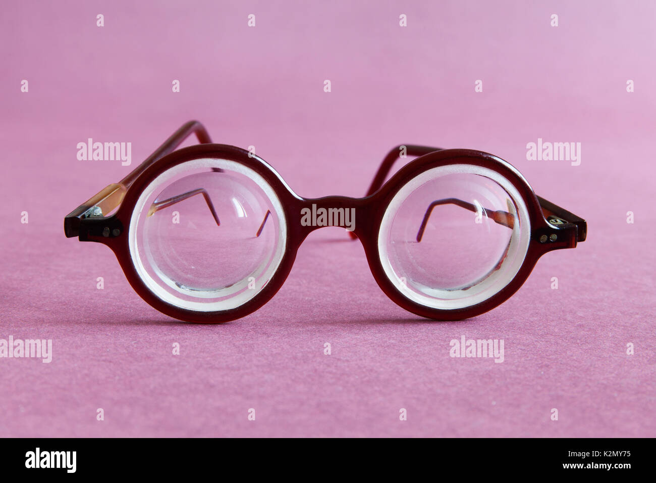 Old fashion design occhiali occhiali in rosa viola lo sfondo della carta.  In stile vintage moda maschile accessori per una visione perfetta. Vista  Macro, profondità di campo, soft focus Foto stock -