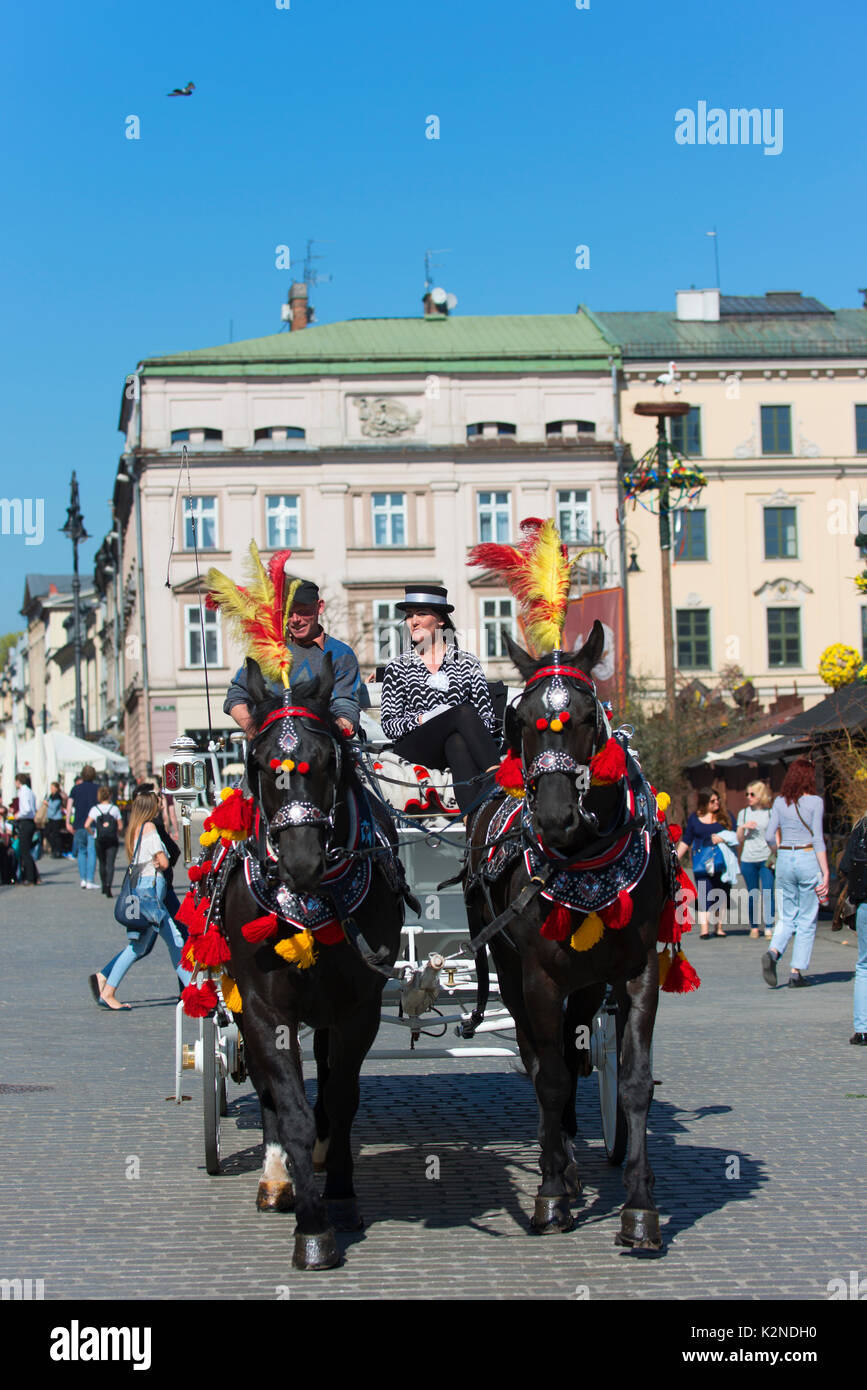 Un carro trainato da cavalli e i suoi gestori di eventi portano i turisti in gita intorno la città vecchia di Cracovia. Foto Stock
