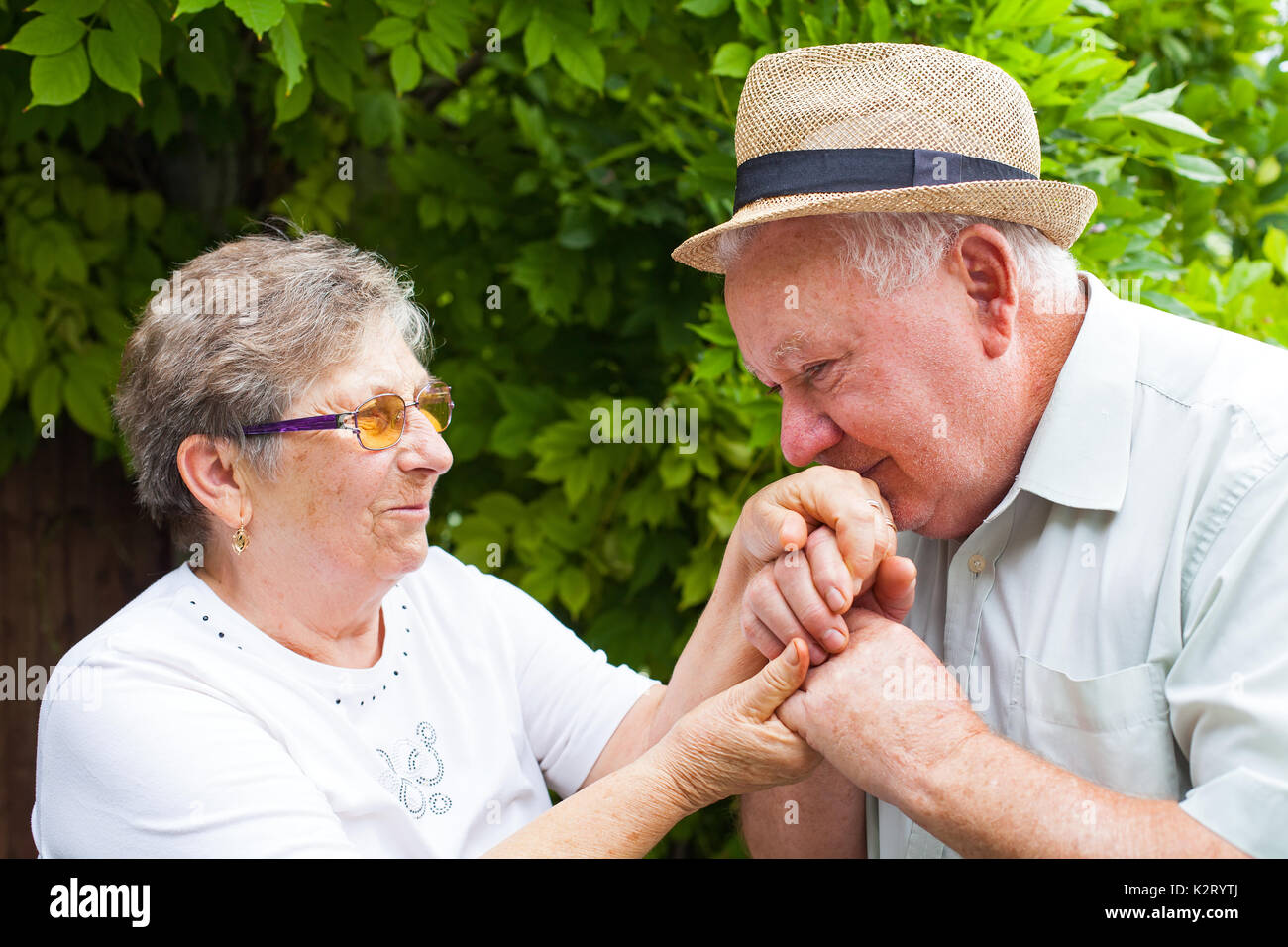 Senior uomo baciando la moglie le mani, coppia di anziani in amore per esterno Foto Stock