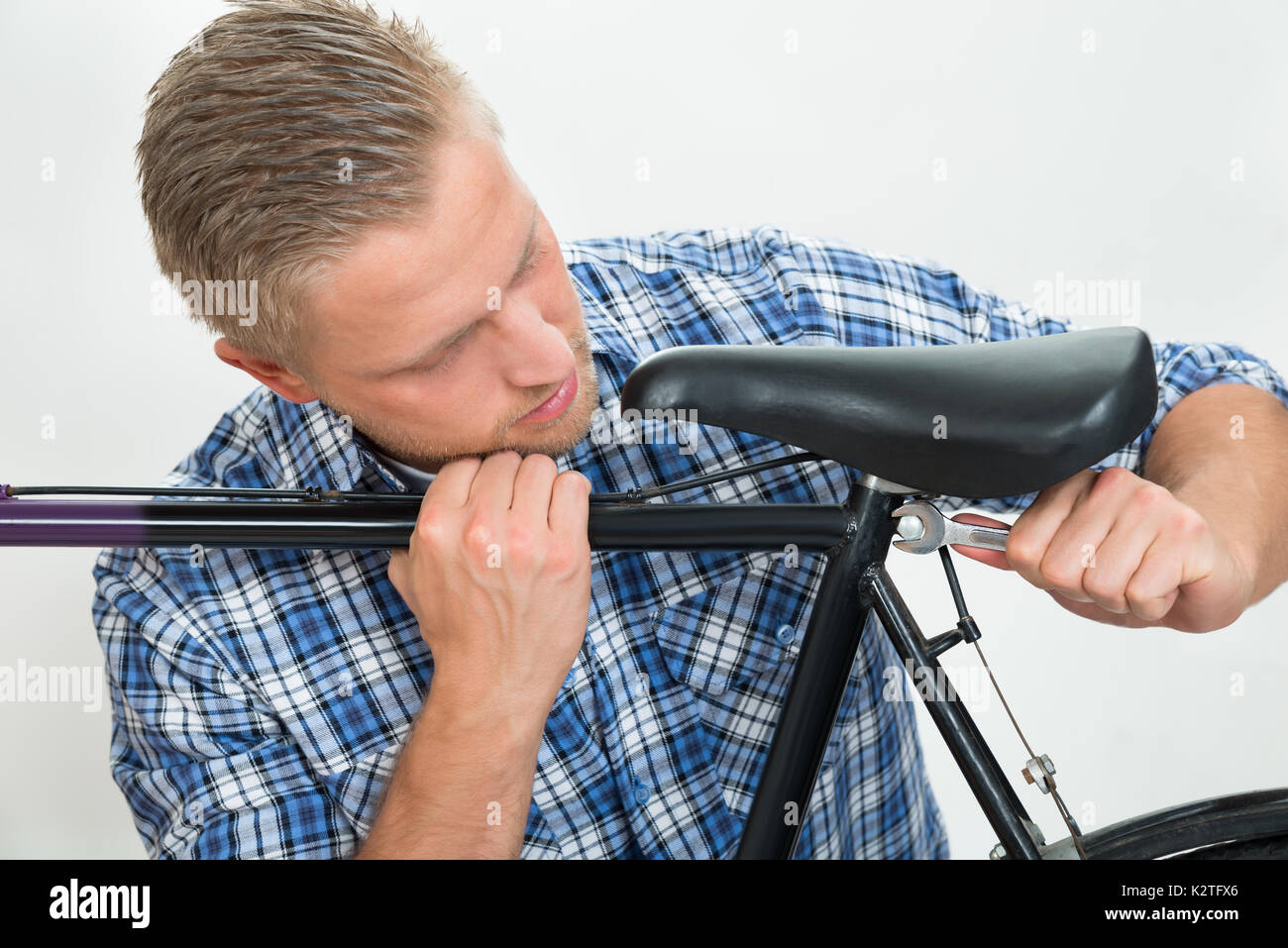 Ritratto di giovane uomo del serraggio delle viti della sella per bicicletta con la chiave Foto Stock