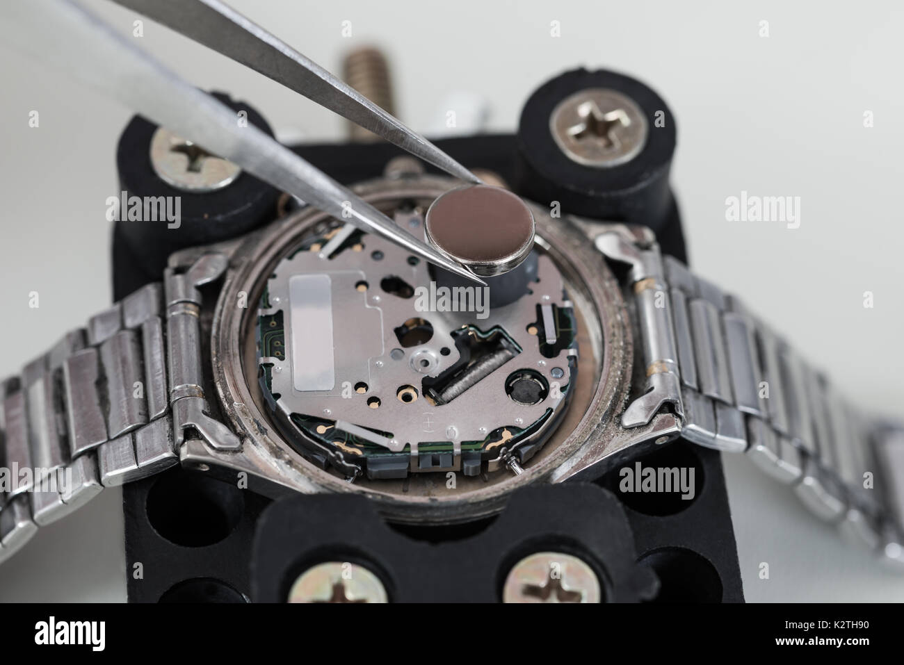 Close-up di pinzette immissione batteria su argento orologio da