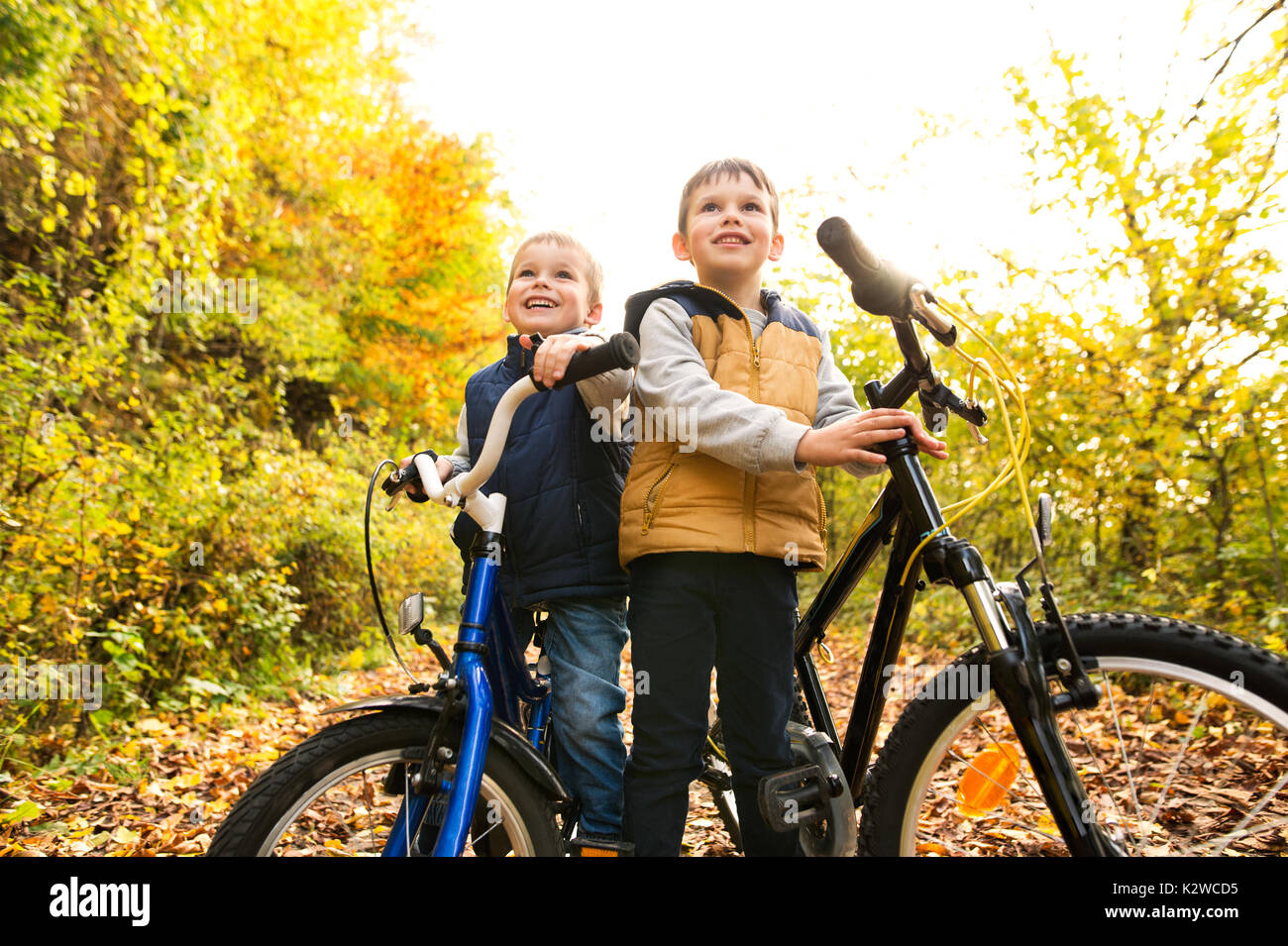 Simpatici ragazzi piccoli in bicicletta nel soleggiato parco d'autunno. Foto Stock