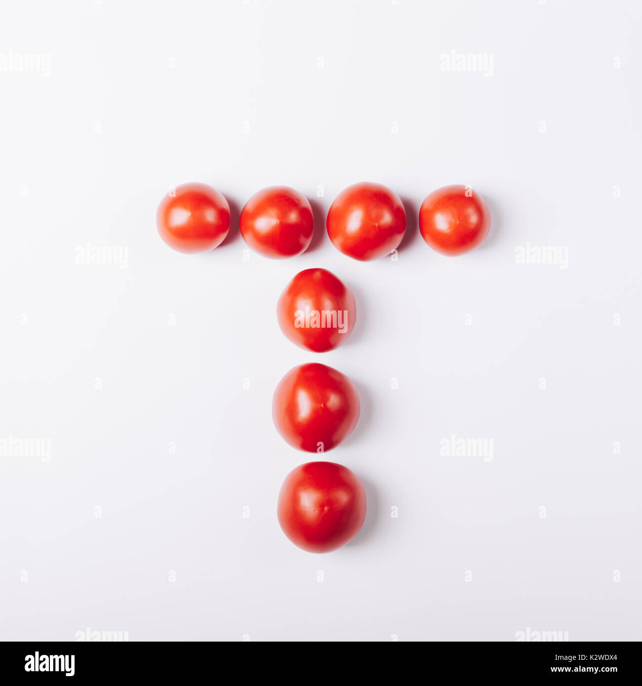 Pomodori rossi nella forma della lettera 'T' su sfondo bianco Foto Stock