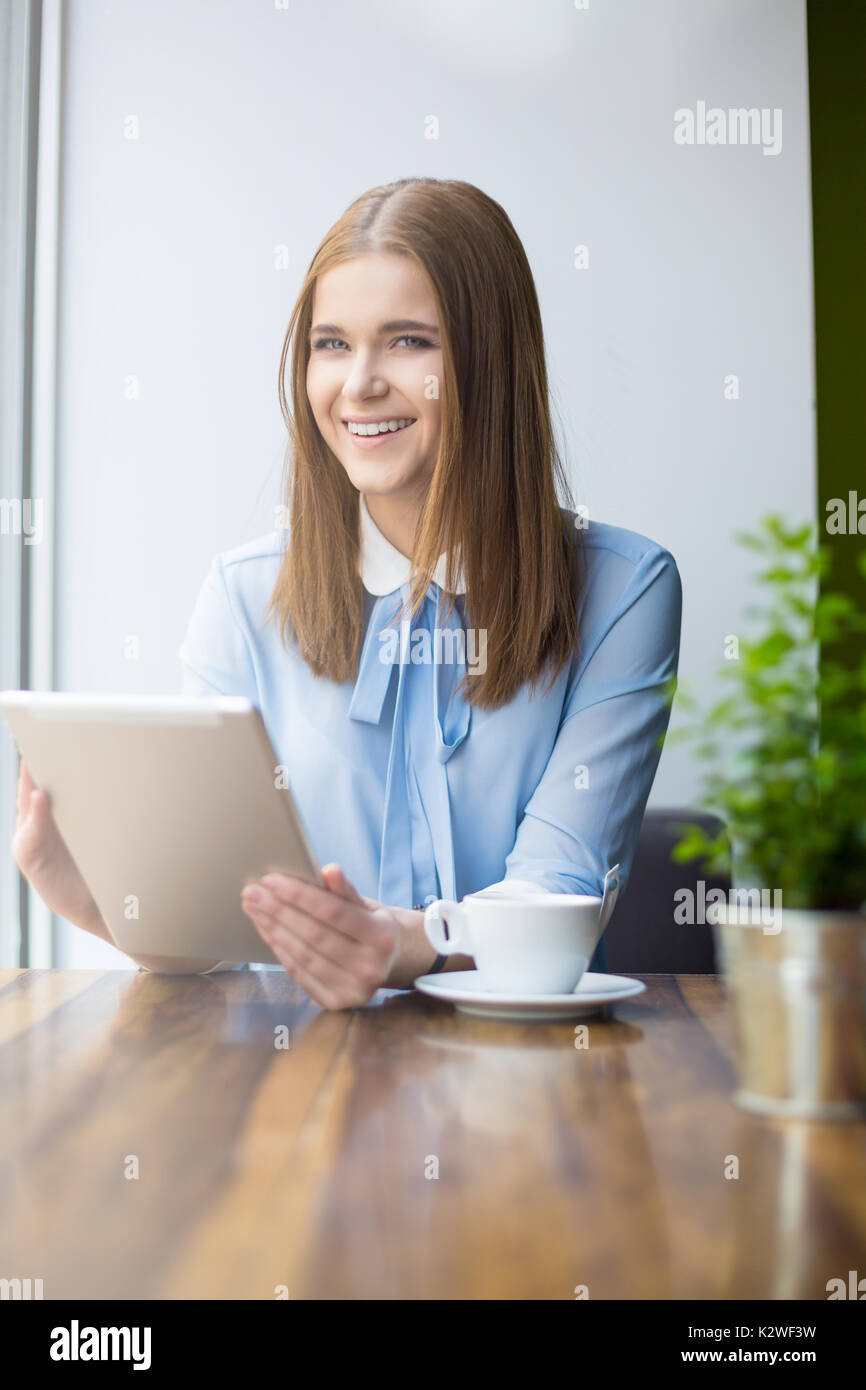 Donna sorridente al cafe con tavoletta digitale Foto Stock