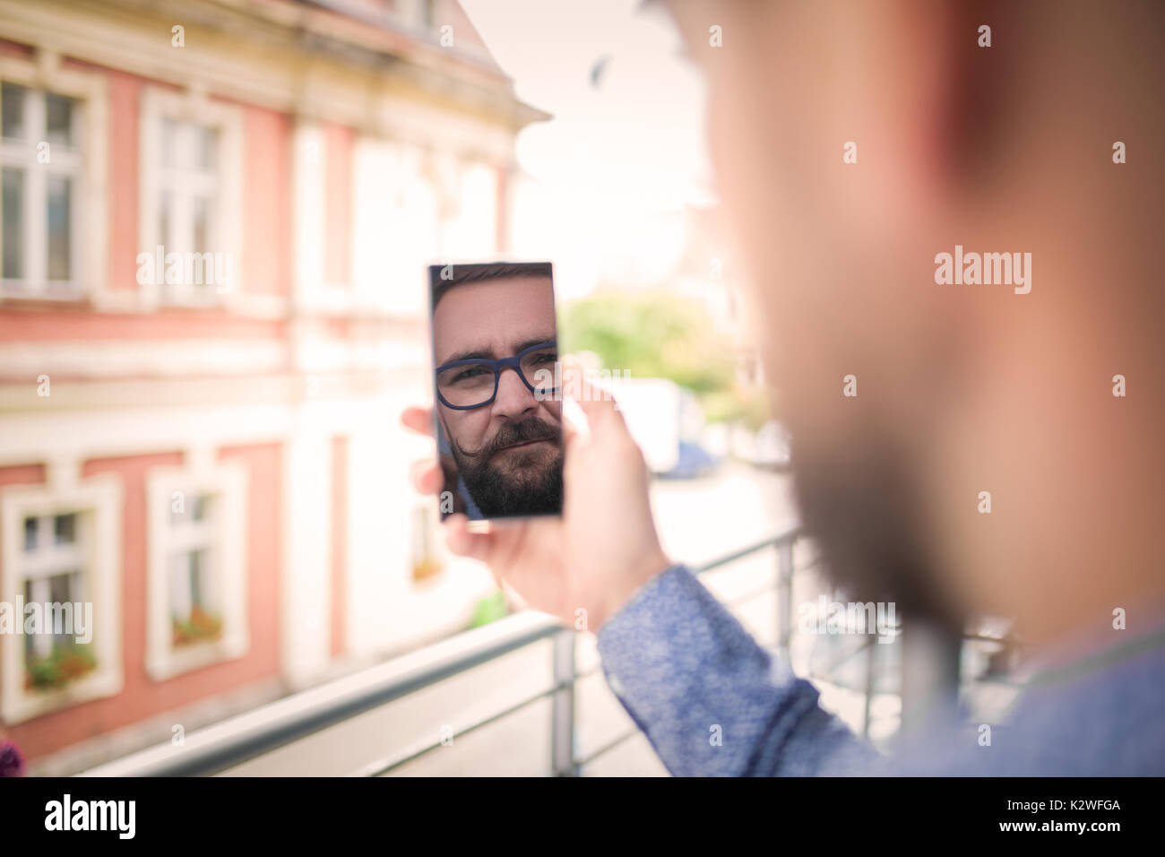 La riflessione di un uomo il suo volto nel telefono cellulare Foto Stock