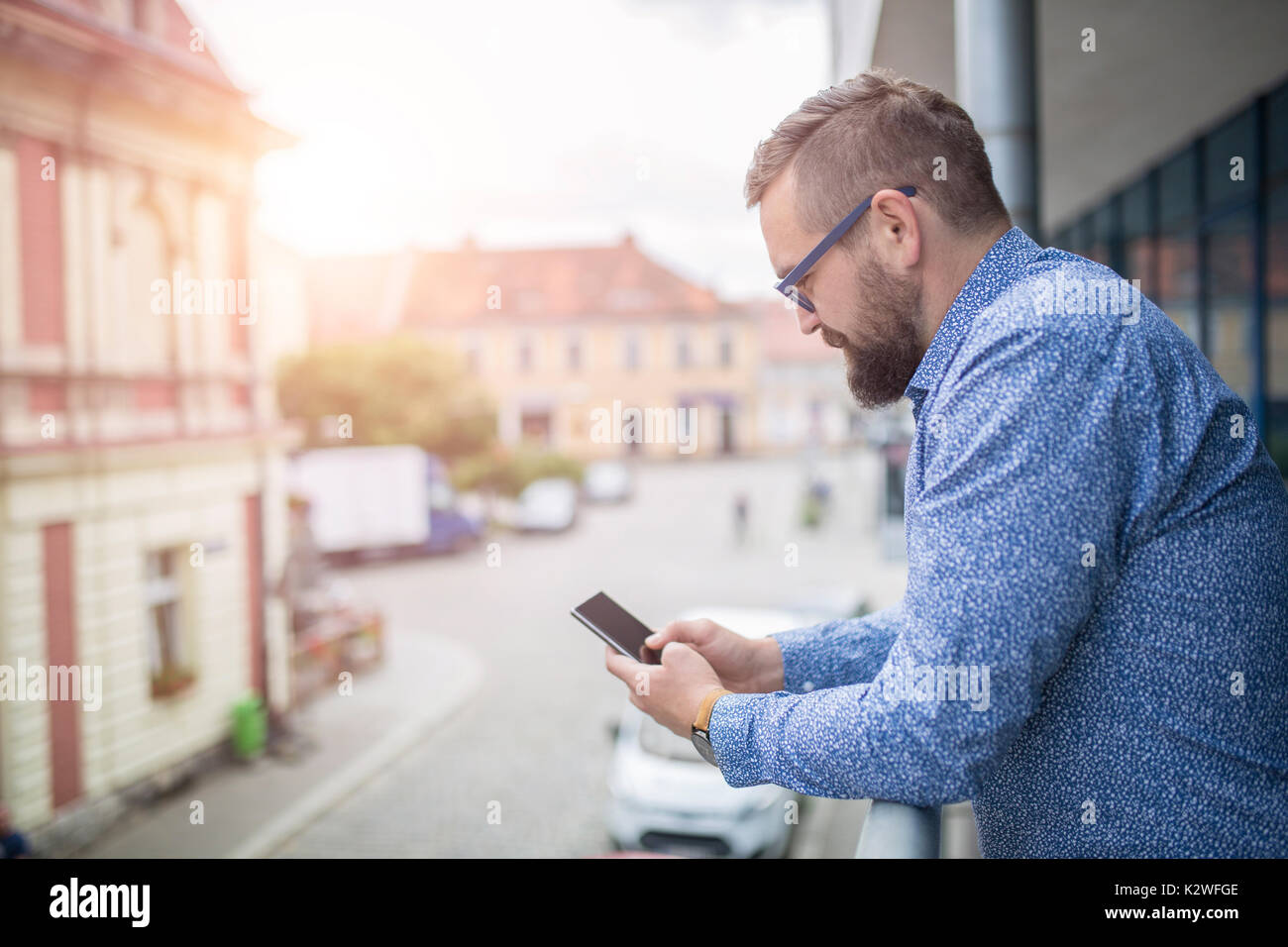 Uomo al balcone e navigare in rete su smart phone Foto Stock