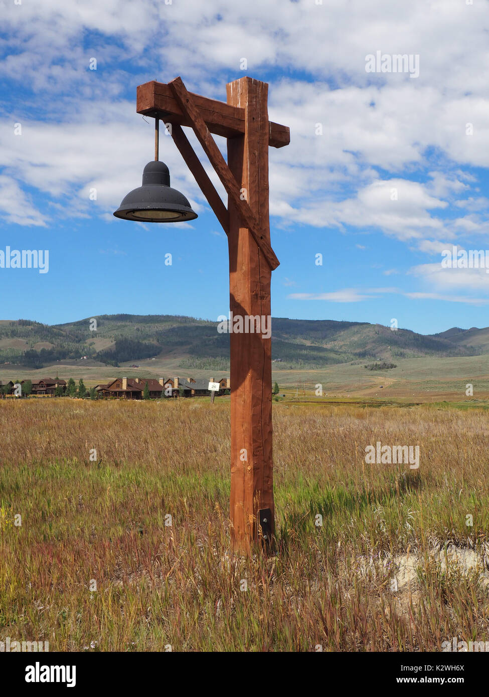 Stile rustico wood street luce su una prateria in Colorado. Vi è un blu brillante il cielo sopra la testa con il bianco puffy nuvole. Sullo sfondo sono mountain Foto Stock