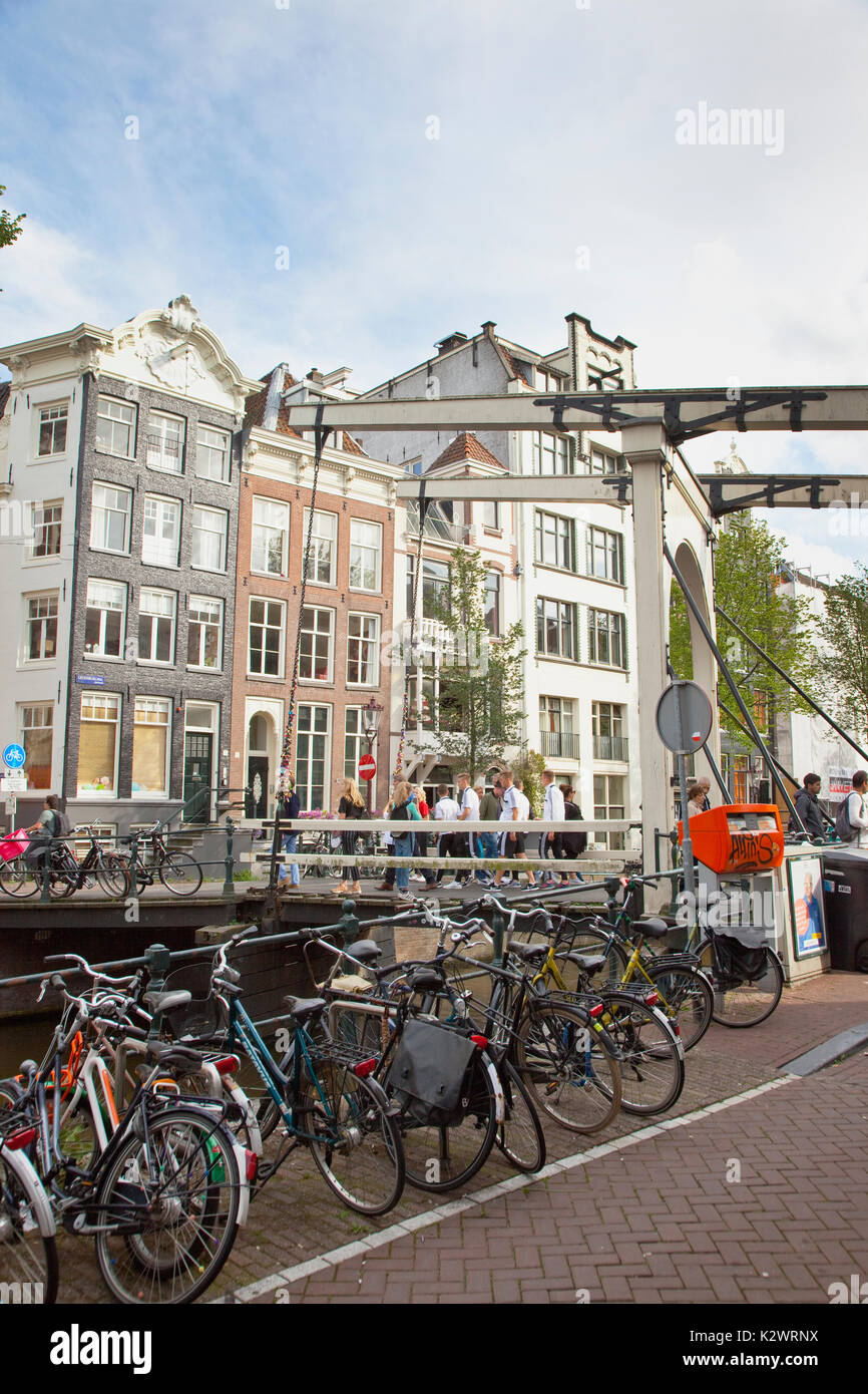 Holland, a nord di Amsterdam, Biciclette parcheggiate accanto al canal con il tipico ponte di sollevamento in background. Foto Stock