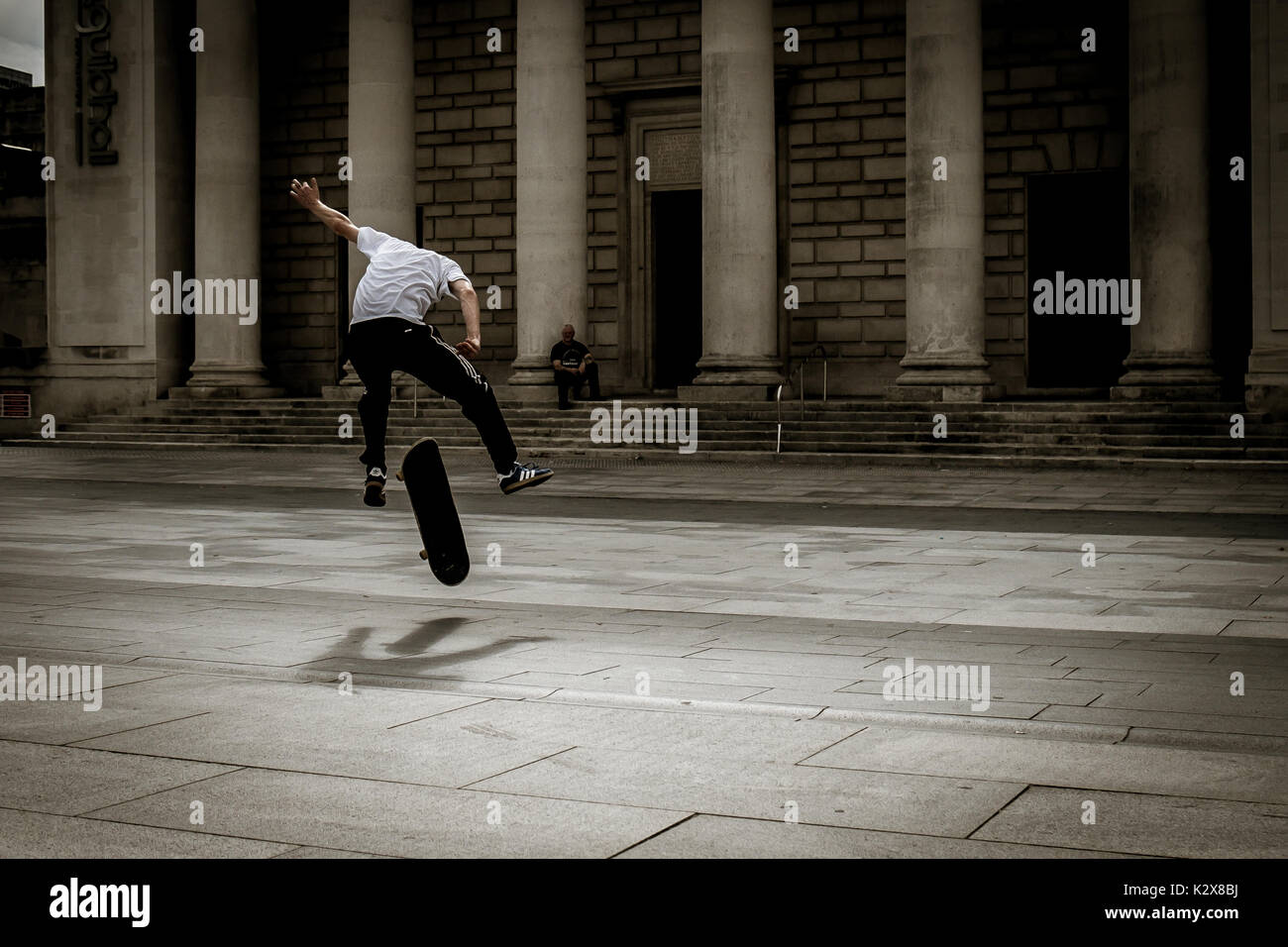 Guidatore di skateboard getting aria - via la terra a metà stunt Foto Stock