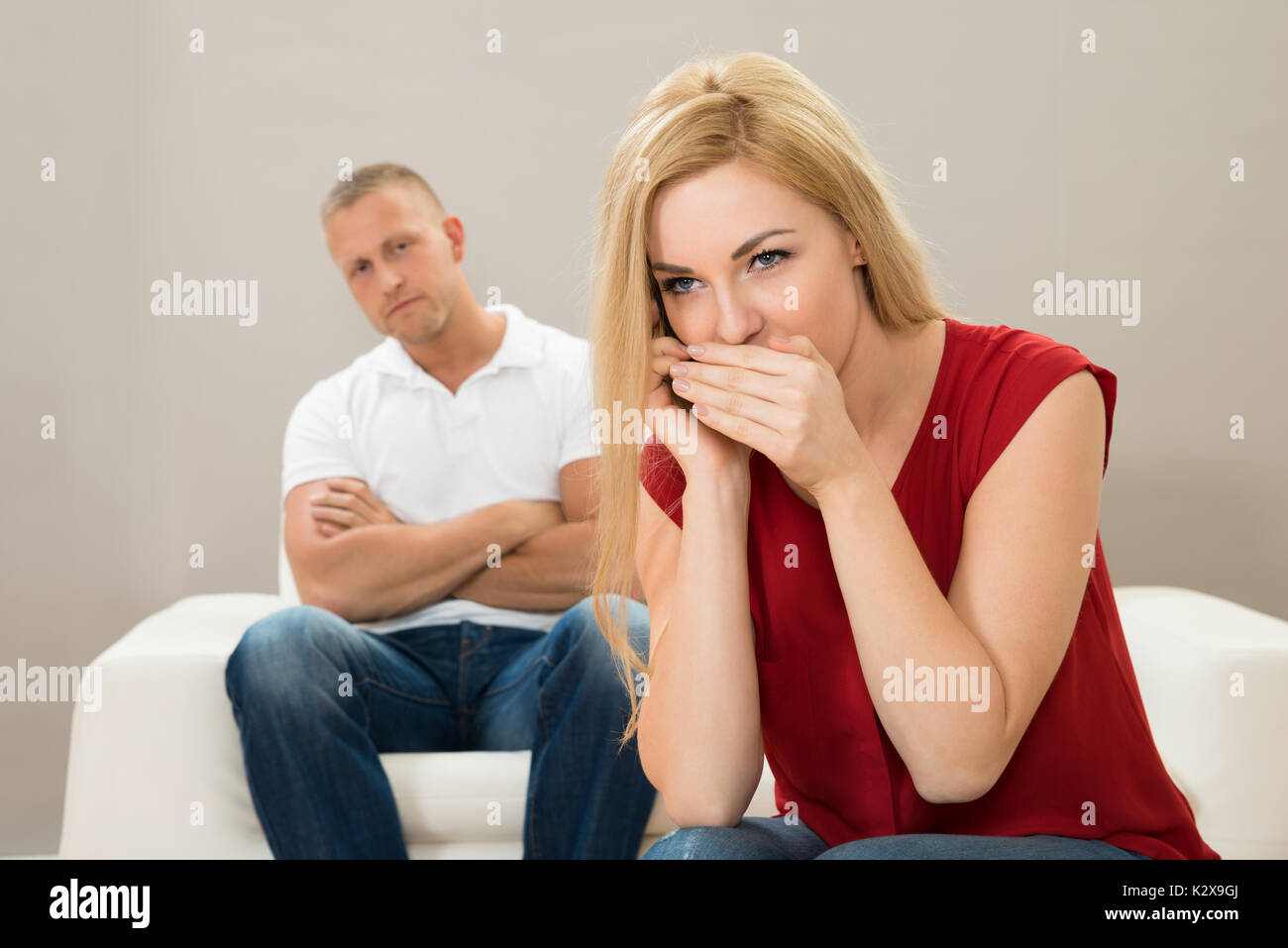 Moglie di parlare in privato con il cellulare mentre il marito seduto sul  divano Foto stock - Alamy