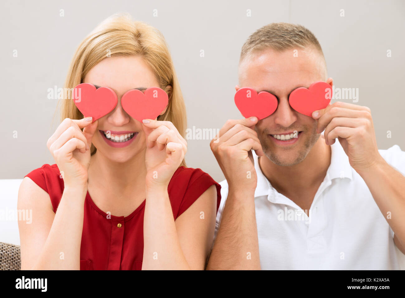 Giovane coppia felice che coprono gli occhi con il cuore rosso Foto Stock