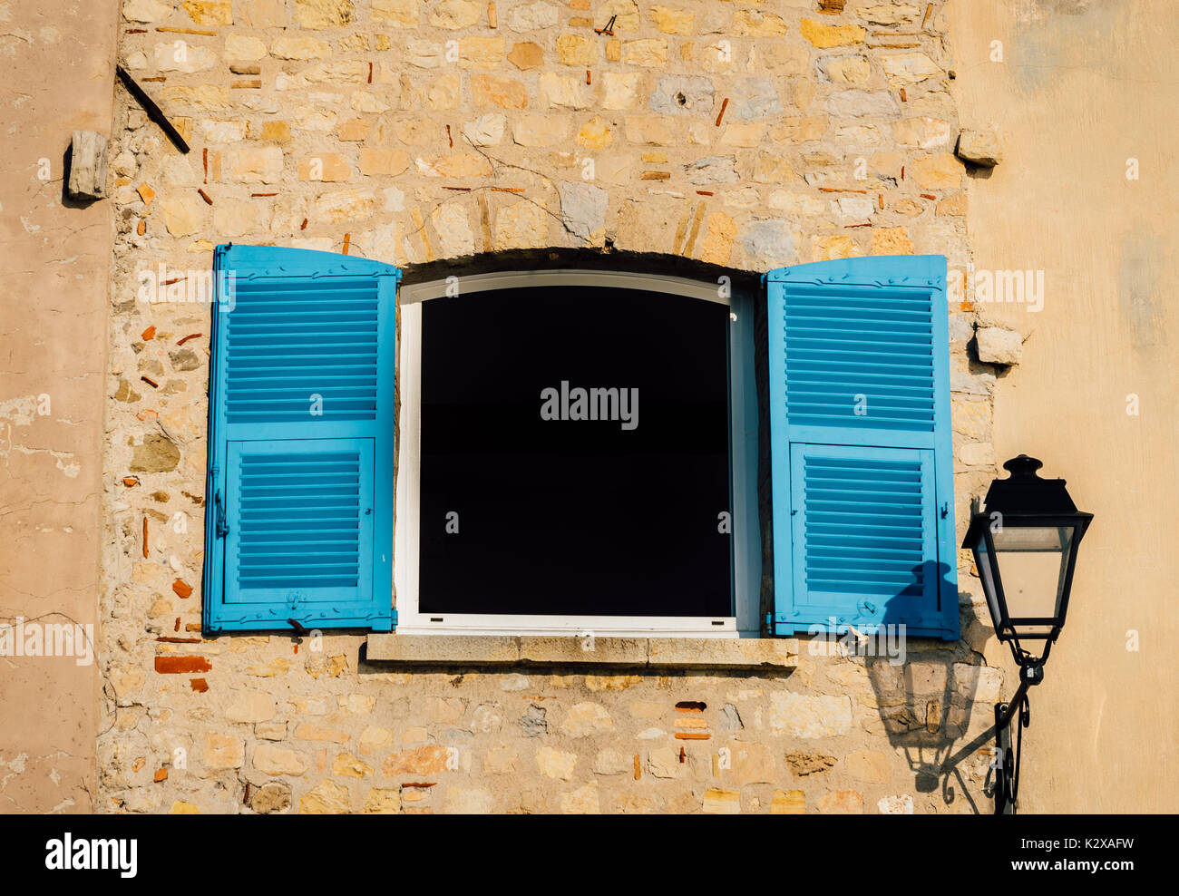 Persiane in blu chiaro con una lampada posta su una parete rustico in Provenza, Francia Foto Stock