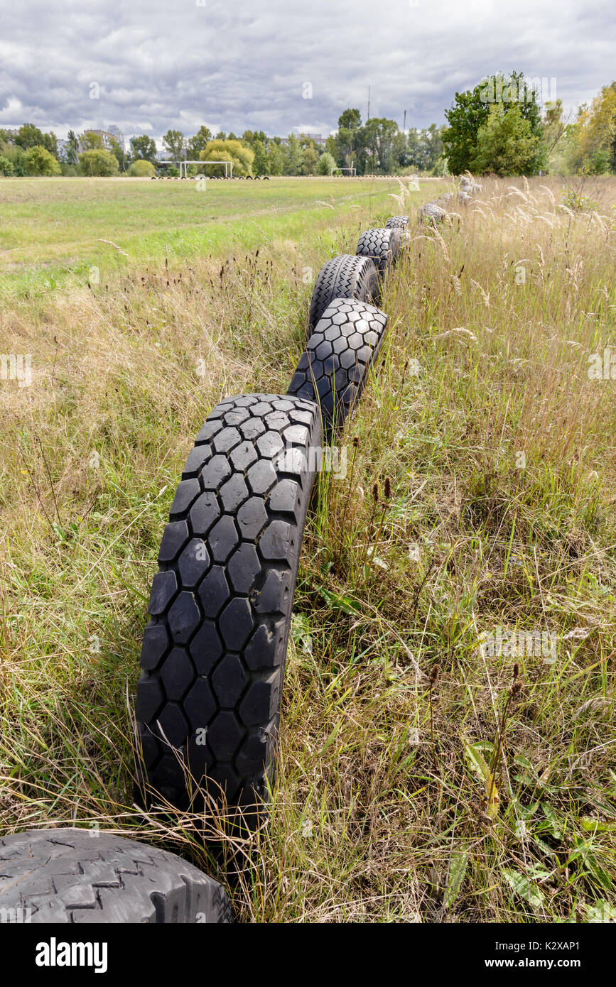 Vecchi pneumatici usati per delineare il perimetro di un campo di calcio Foto Stock