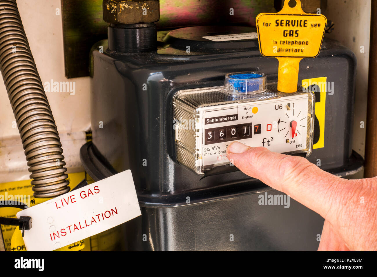 All'interno di un contatore di gas credenza con un tasto giallo sulla parte superiore del misuratore a tenuta stagna e un dito puntato al momento del consumo di lettura. East Midlands, Inghilterra, Regno Unito. Foto Stock