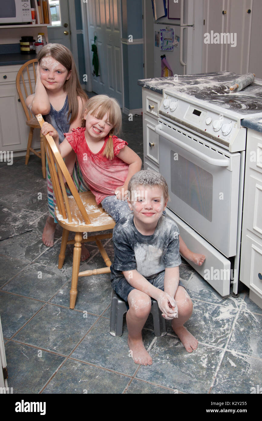 Tre bambini cattivi che hanno appena fatto un pasticcio in cucina sedersi  accanto al forno cercando felice Foto stock - Alamy