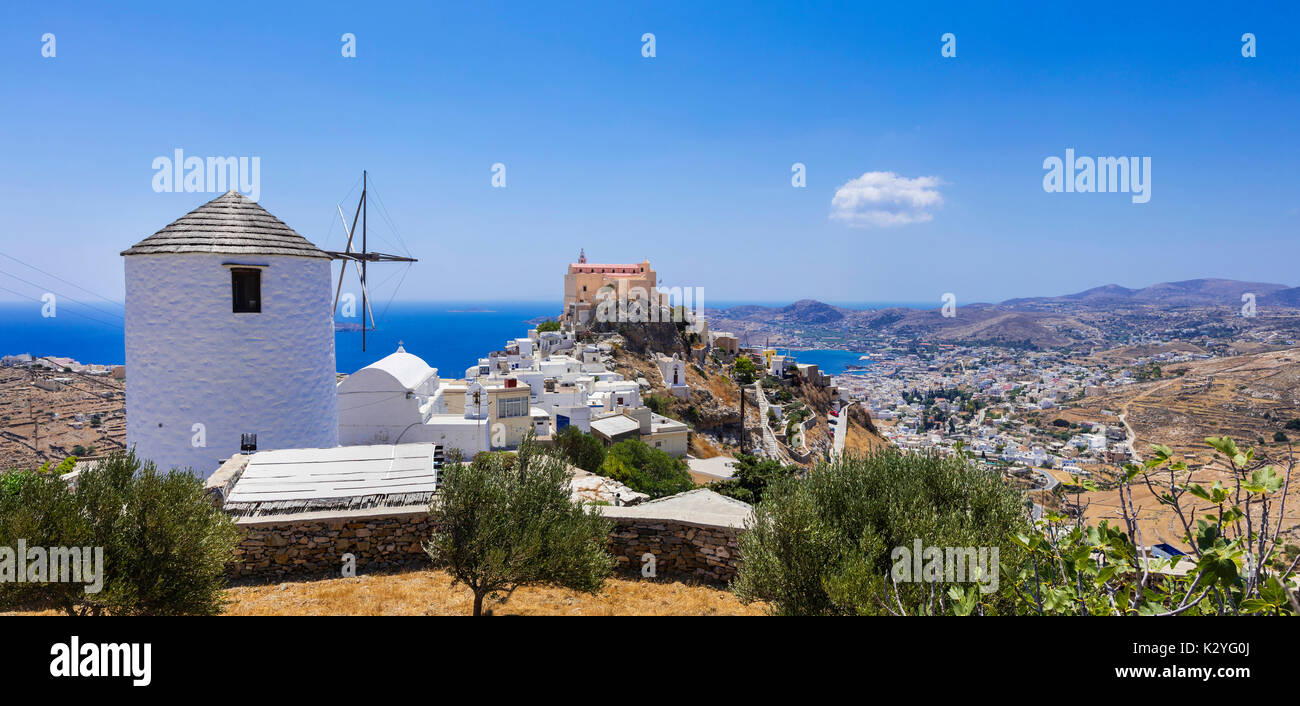 Mulino a vento tradizionale e case colorate in Syros Island, Grecia. Foto Stock