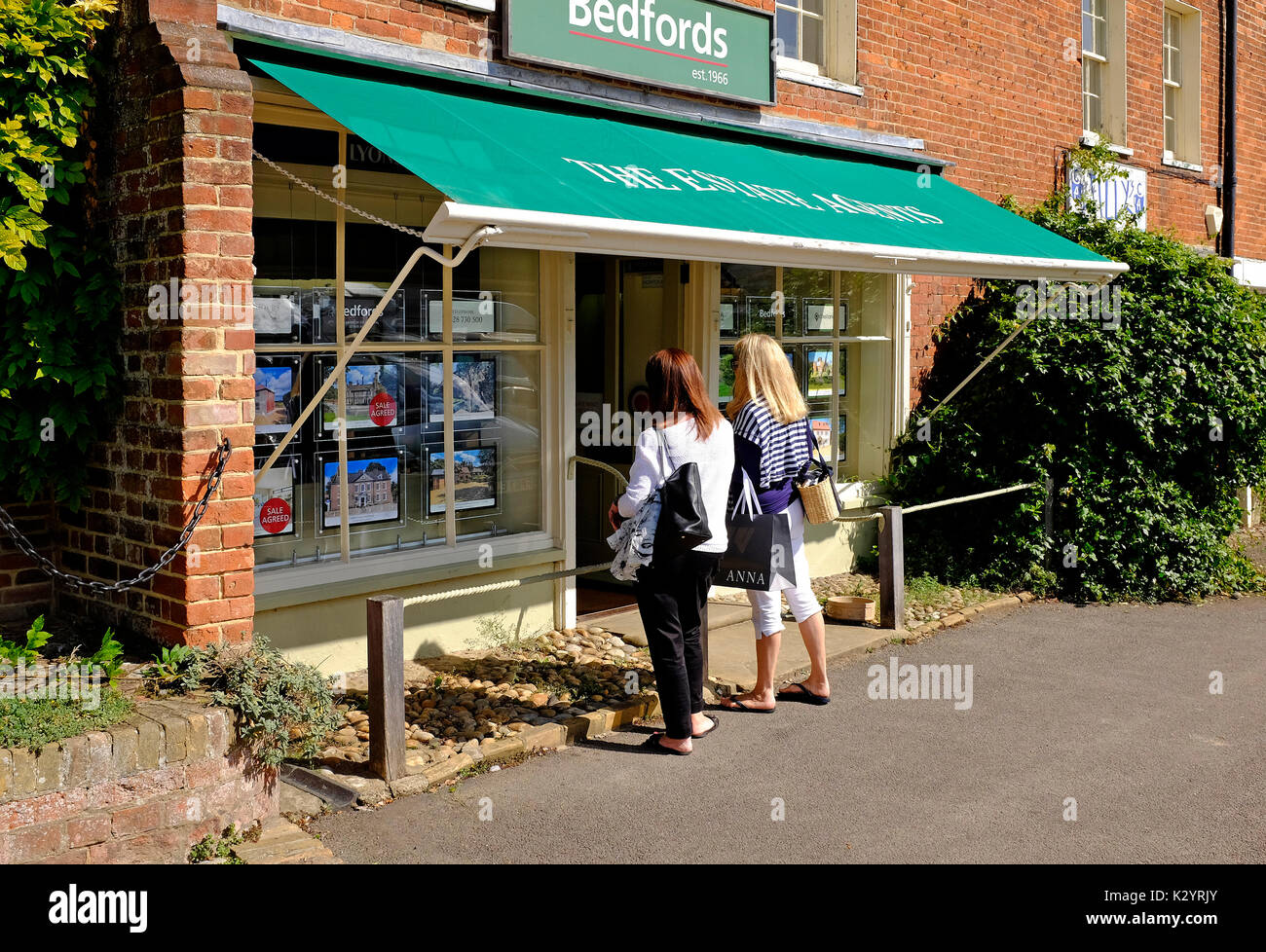 Due donne alla ricerca di agenti immobiliari finestra, burnham market, North Norfolk, Inghilterra Foto Stock