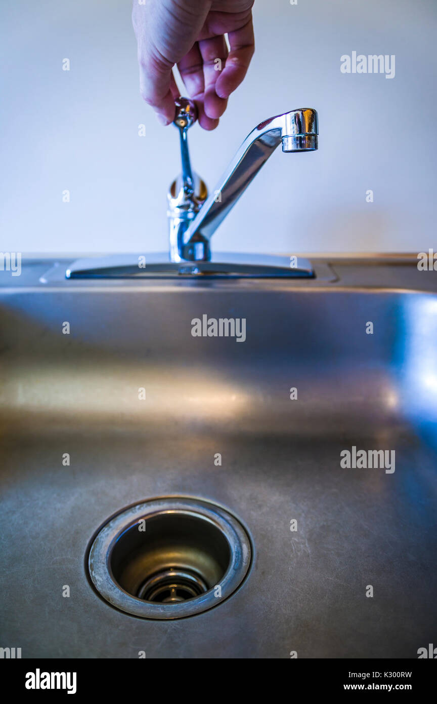Una mano su per accendere un rubinetto d'acqua. Foto Stock