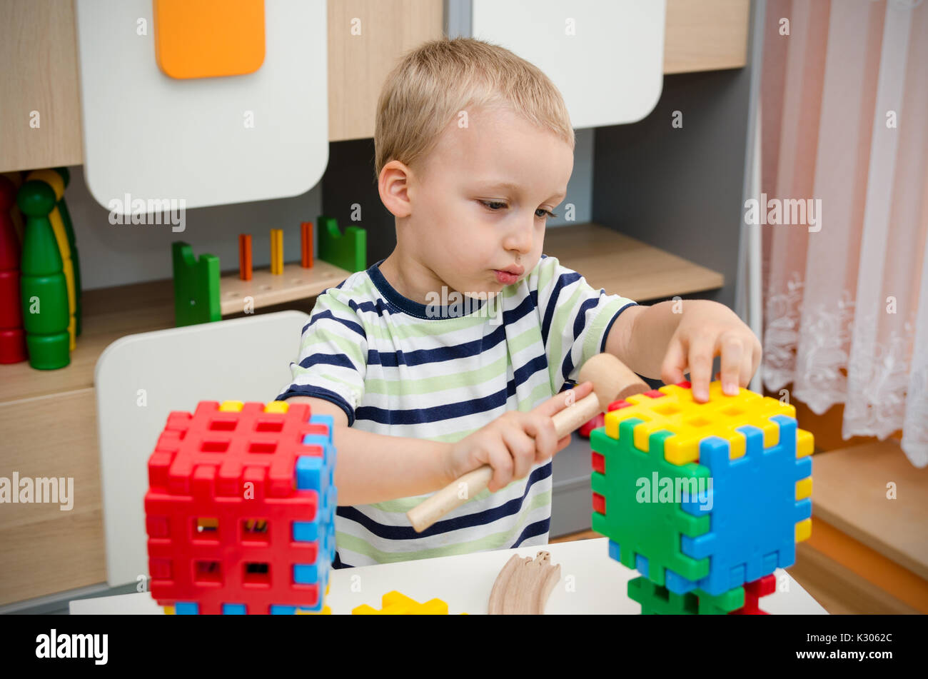 Little Boy giocando con i blocchi su un tavolo. bambino ragazzo giovane ragazzo diurni sala giochi di blocco concetto build Foto Stock