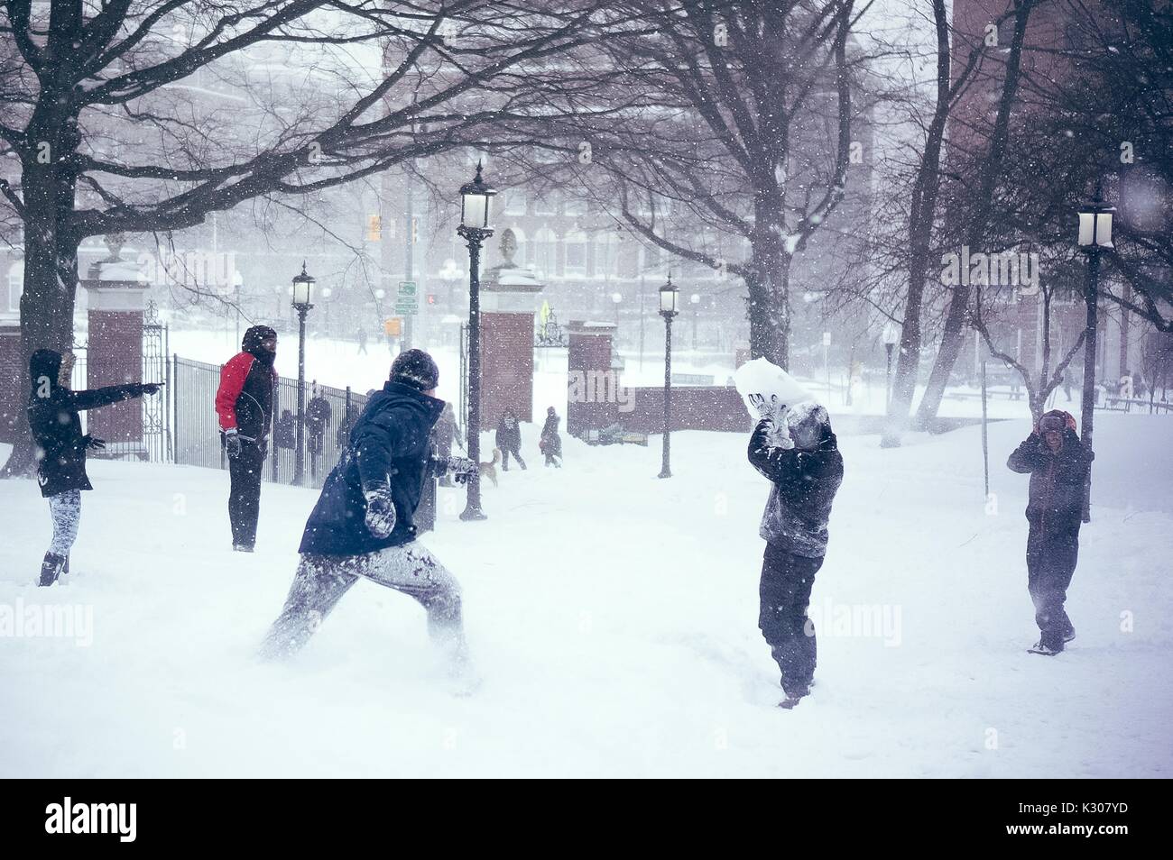 Gli studenti correre e giocare durante una massiccia lotta con le palle di neve, mentre uno studente solleva un enorme cumulo di neve sopra la sua testa, in un giorno di neve alla Johns Hopkins University, Baltimora, Maryland, 2016. Foto Stock