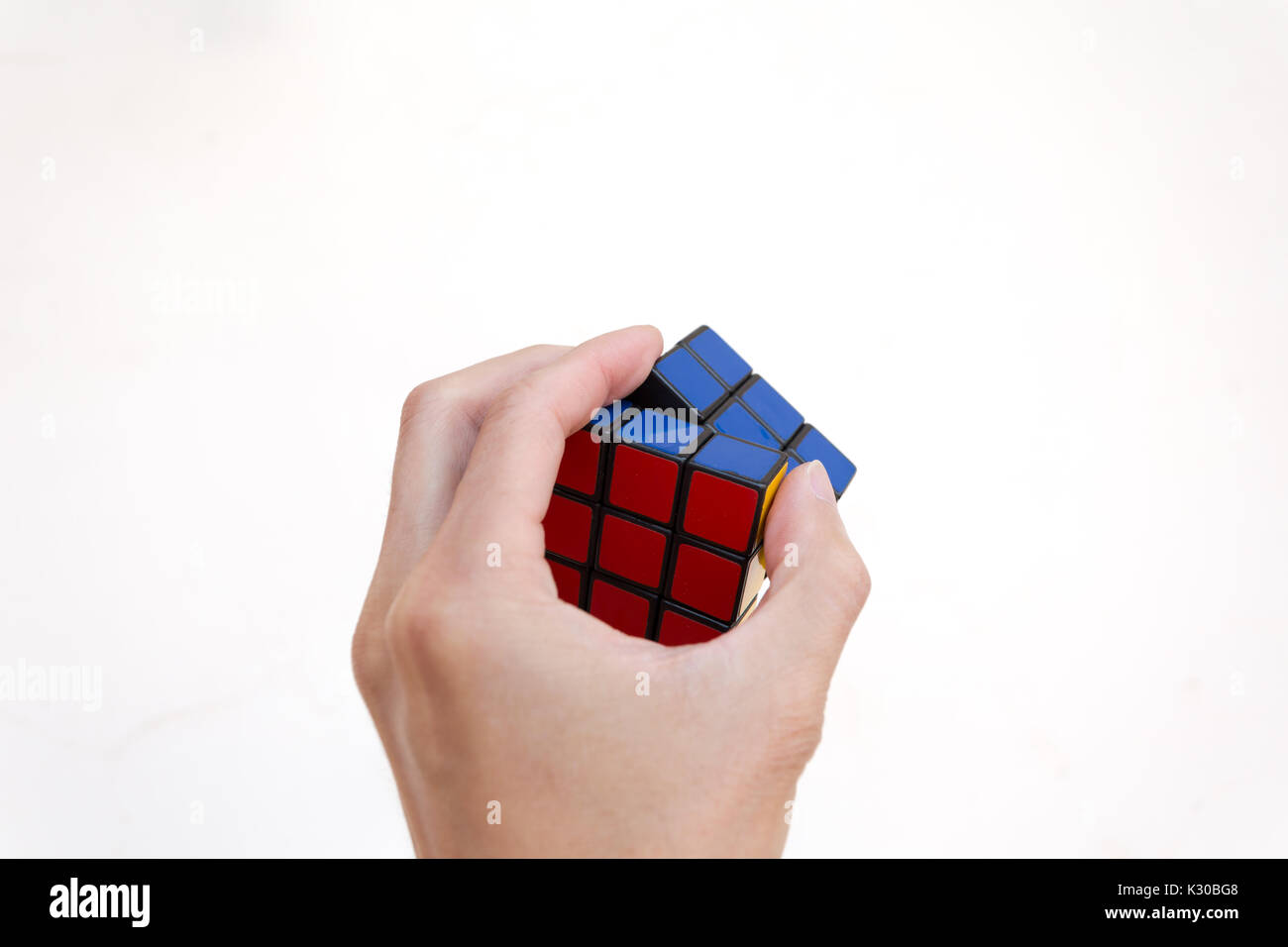 Magic o Cubo di Rubik Cubo magico, una mano a risolvere, contro uno sfondo bianco Foto Stock