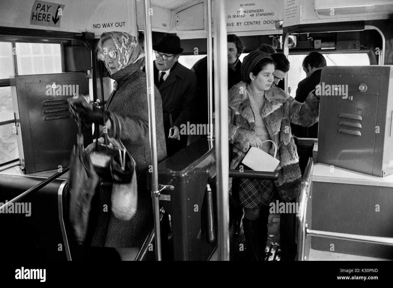 Macchina per i biglietti degli autobus 1970s di Londra all'interno dell'autobus. Pendolari e acquirenti che salgono su un autobus della London Transport. I conduttori degli autobus che distribuiscono i biglietti sono stati fermati e le biglietterie ora prendono il loro posto. 1970S UK HOMER SYKES Foto Stock