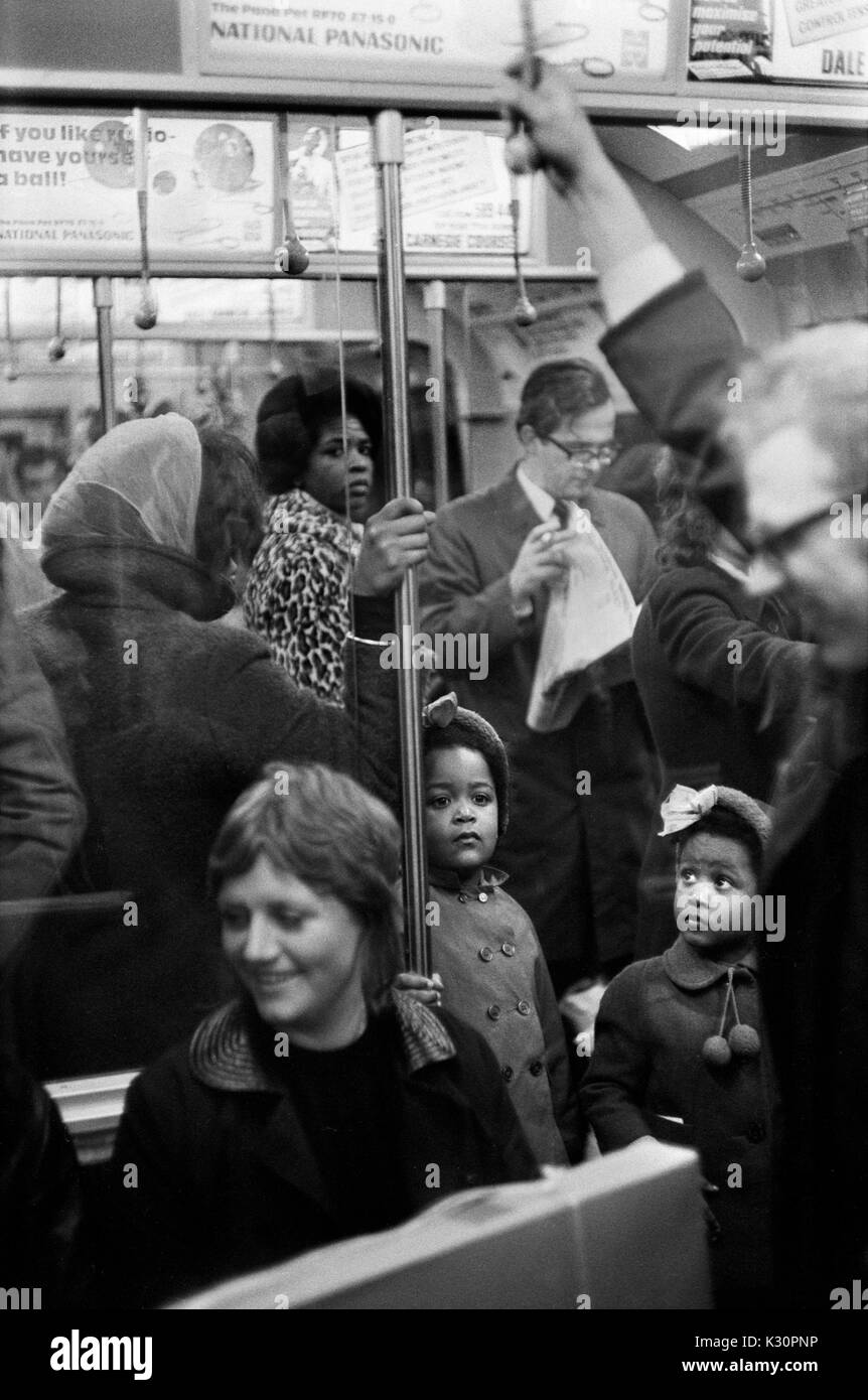 Metropolitana di Londra pendolari famiglia nera due bambini sorelle e madre dietro di loro in un affollato treno sotterraneo. Nuovi immigrati in Gran Bretagna. Inghilterra 1970 Regno Unito 1970s HOMER SYKES Foto Stock