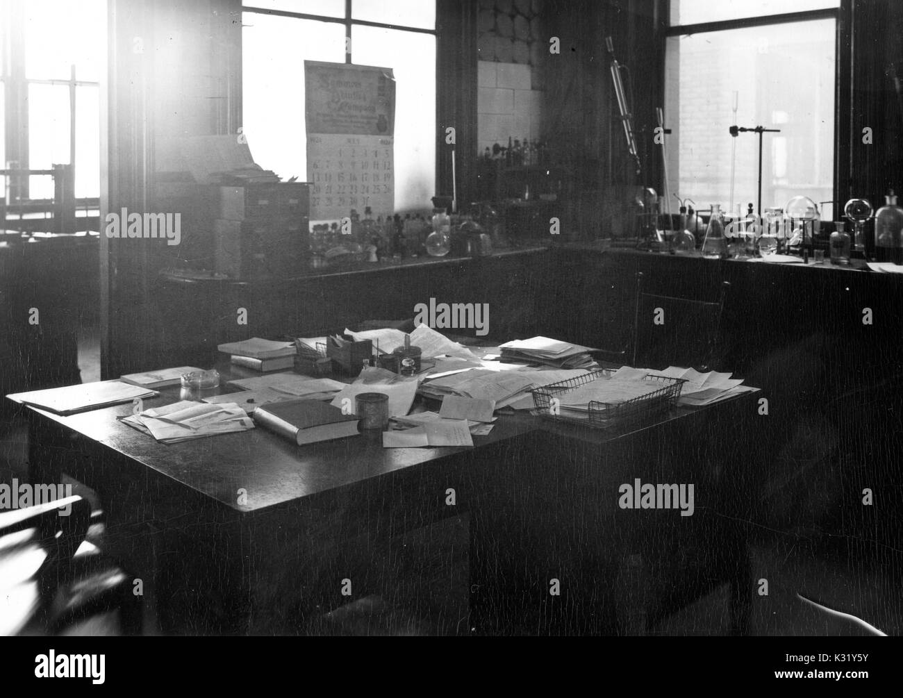 Scala di grigi fotografia di interni dell'ufficio di Ebenezer Emmett Reid, chimico e fisico presso la Johns Hopkins University, con documenti sparsi su una scrivania e vetreria di chimica e di attrezzature di una panca dietro, all'interno dell'edificio di chimica presso Old Campus, Baltimore, Maryland, 1924. Foto Stock