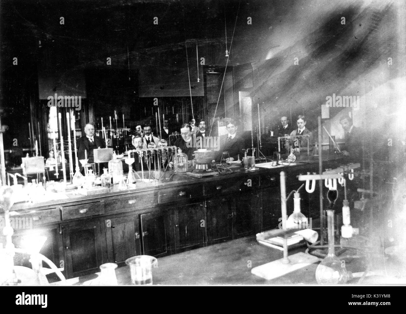 Fotografia in scala di grigi di studenti e professori che lavorano in un'Organic Chemistry Laboratory con bicchieri, provette, e altri dispositivi, in un edificio di chimica dal vecchio Campus presso la Johns Hopkins University, Baltimora, Maryland, 1900. Foto Stock