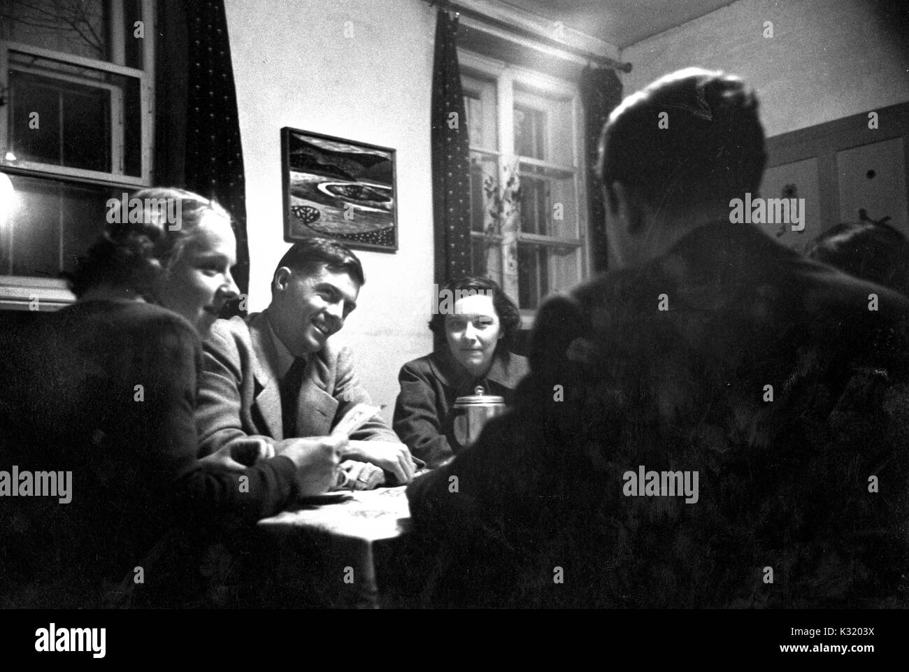 Seppia candida fotografia di John Richard Cary, professore di letteratura tedesca presso la Johns Hopkins University e ardente Quaker, sorridenti mentre si è seduti a un tavolo con un gruppo di studenti maschi e femmine, Monaco di Baviera, Germania, marzo 1954. Foto Stock