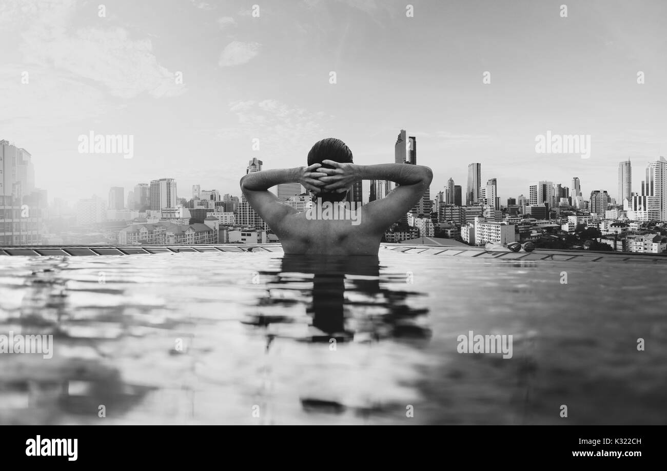 Un uomo di rilassarsi nella piscina sotto nella città, in bianco e nero Foto Stock