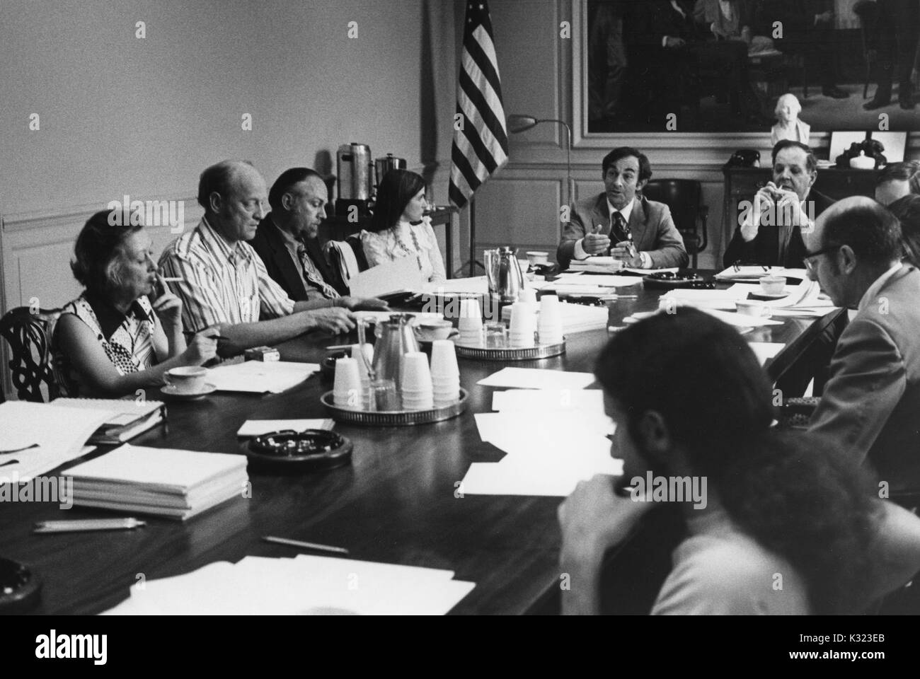 I membri di facoltà e administration presso la Johns Hopkins University e Goucher College si riuniscono per un incontro a un lungo tavolo da conferenza con le carte, tazze da caffè, e portacenere sparse su tutta la parte superiore, Baltimore, Maryland, 1975. Foto Stock