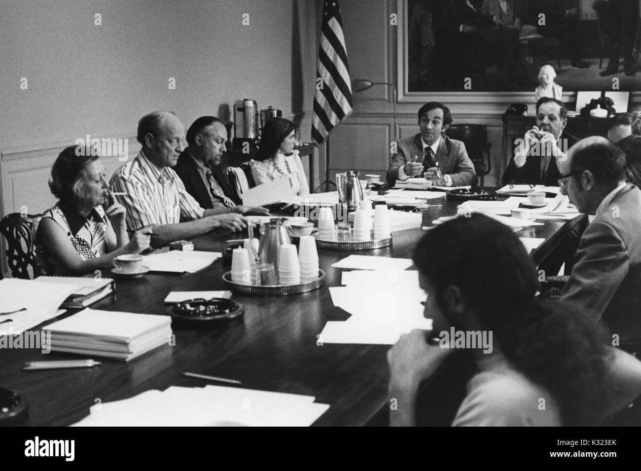 I membri di facoltà e administration presso la Johns Hopkins University e Goucher College si riuniscono per un incontro a un lungo tavolo da conferenza con le carte, tazze da caffè, e portacenere sparse su tutta la parte superiore, Baltimore, Maryland, 1975. Foto Stock