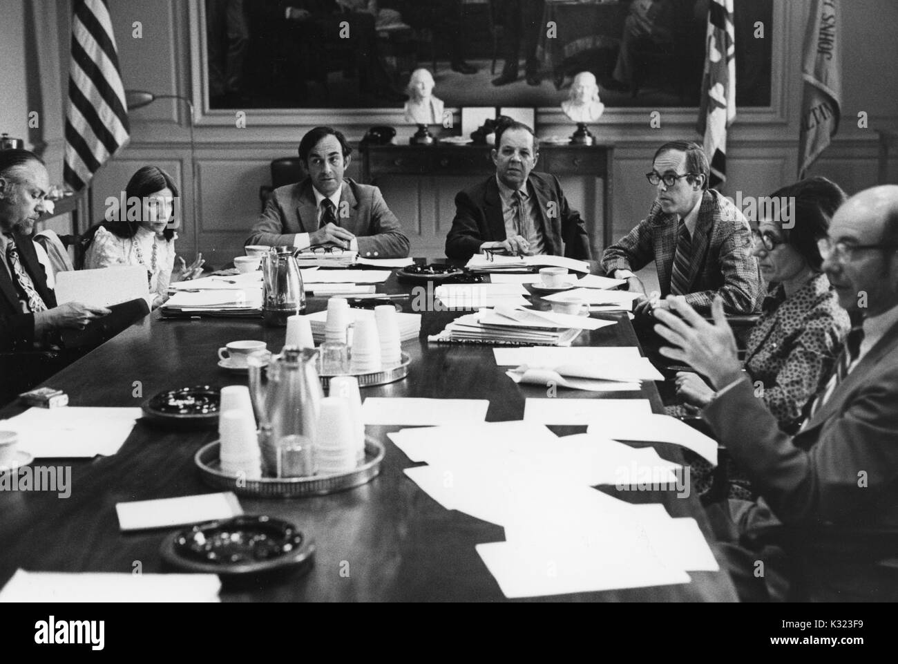 I membri di facoltà e administration presso la Johns Hopkins University e Goucher College si riuniscono per un incontro a un lungo tavolo da conferenza con le carte, tazze da caffè, e portacenere sparse su tutta la parte superiore, Baltimore, Maryland, 1975. Foto Stock