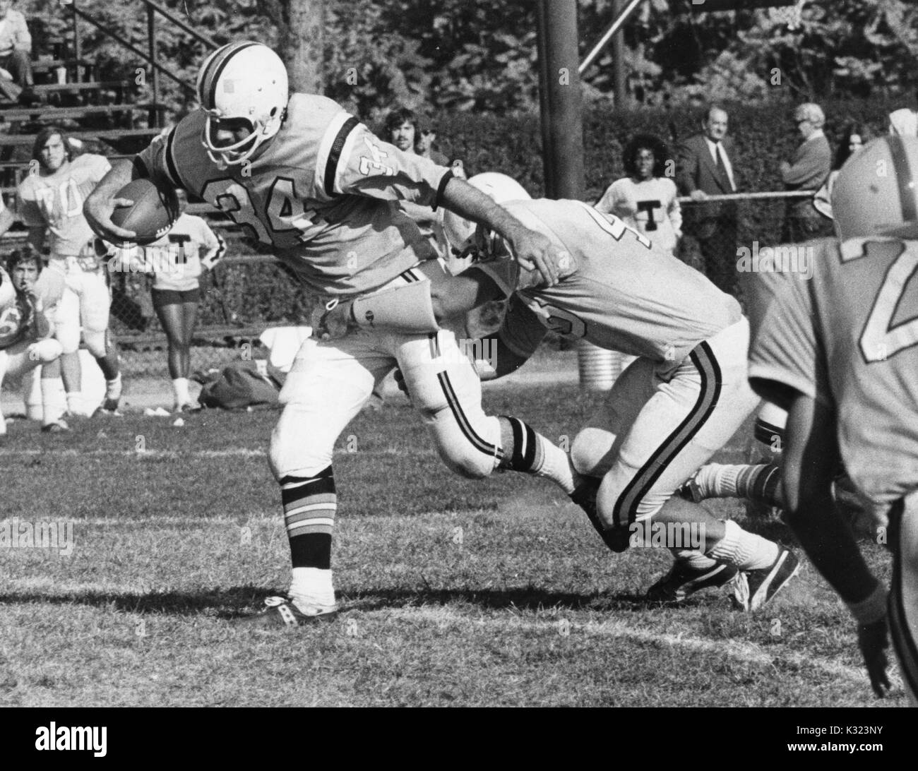 Un Johns Hopkins University giocatore di football di affrontare un giocatore della squadra avversaria con il calcio con il giocatore e ventole sull'emarginare visibile in fondo alla Johns Hopkins University, Baltimora, Maryland, 1980. Foto Stock